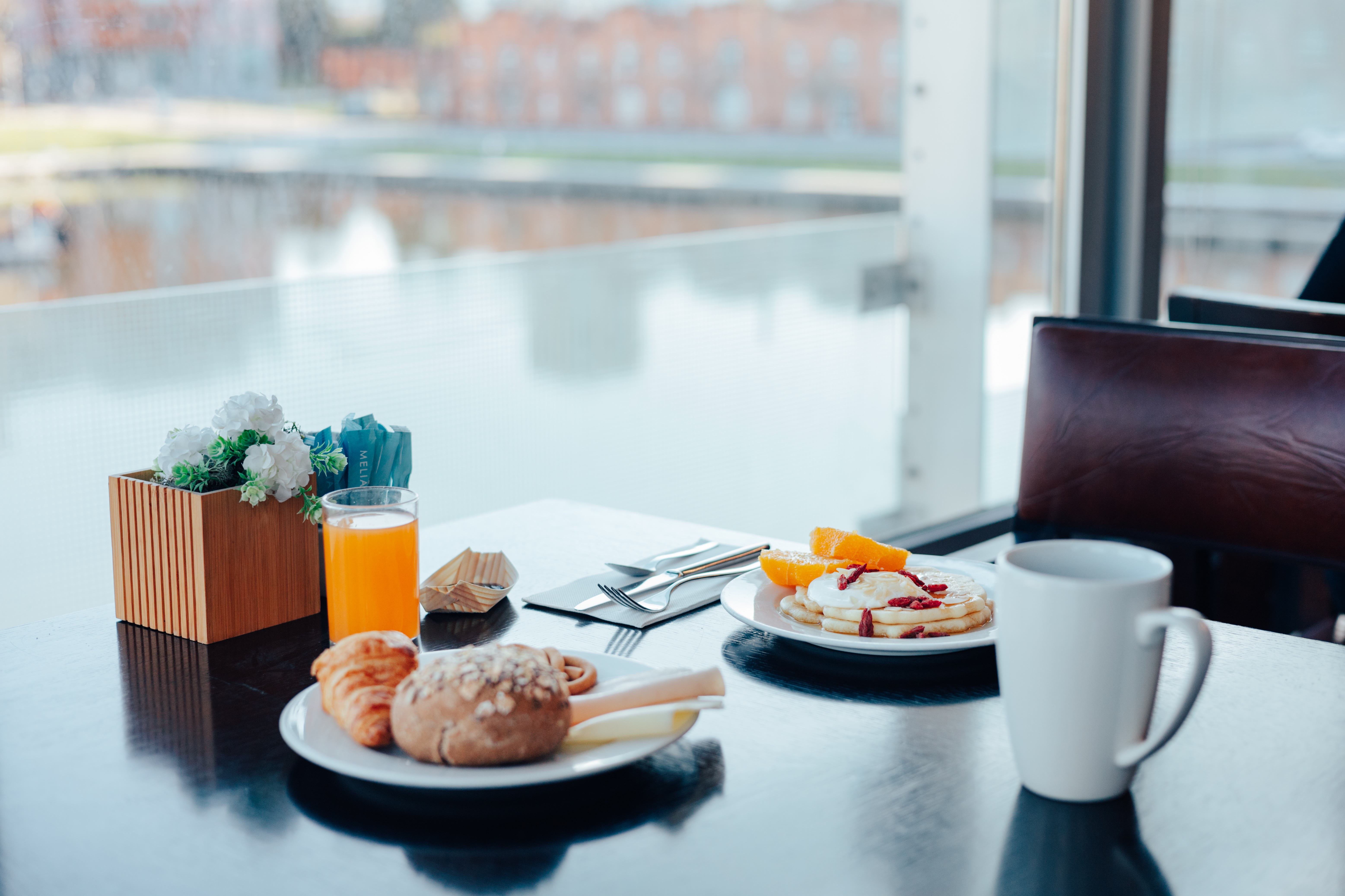 Meliá hotel breakfast: pancakes, croissant, orange juice, scenic view.