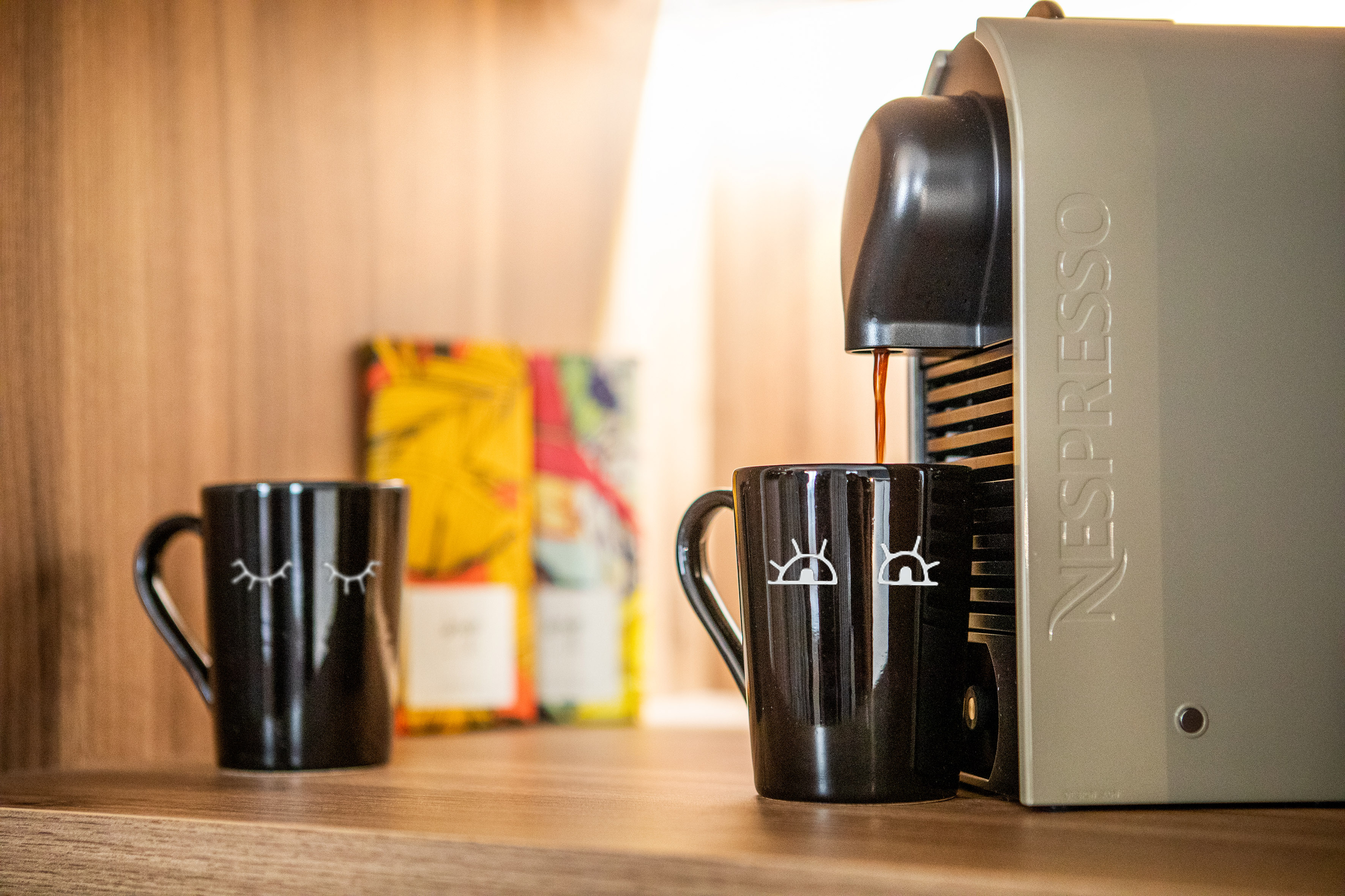 Nespresso coffee machine brewing into a black mug with eye design.