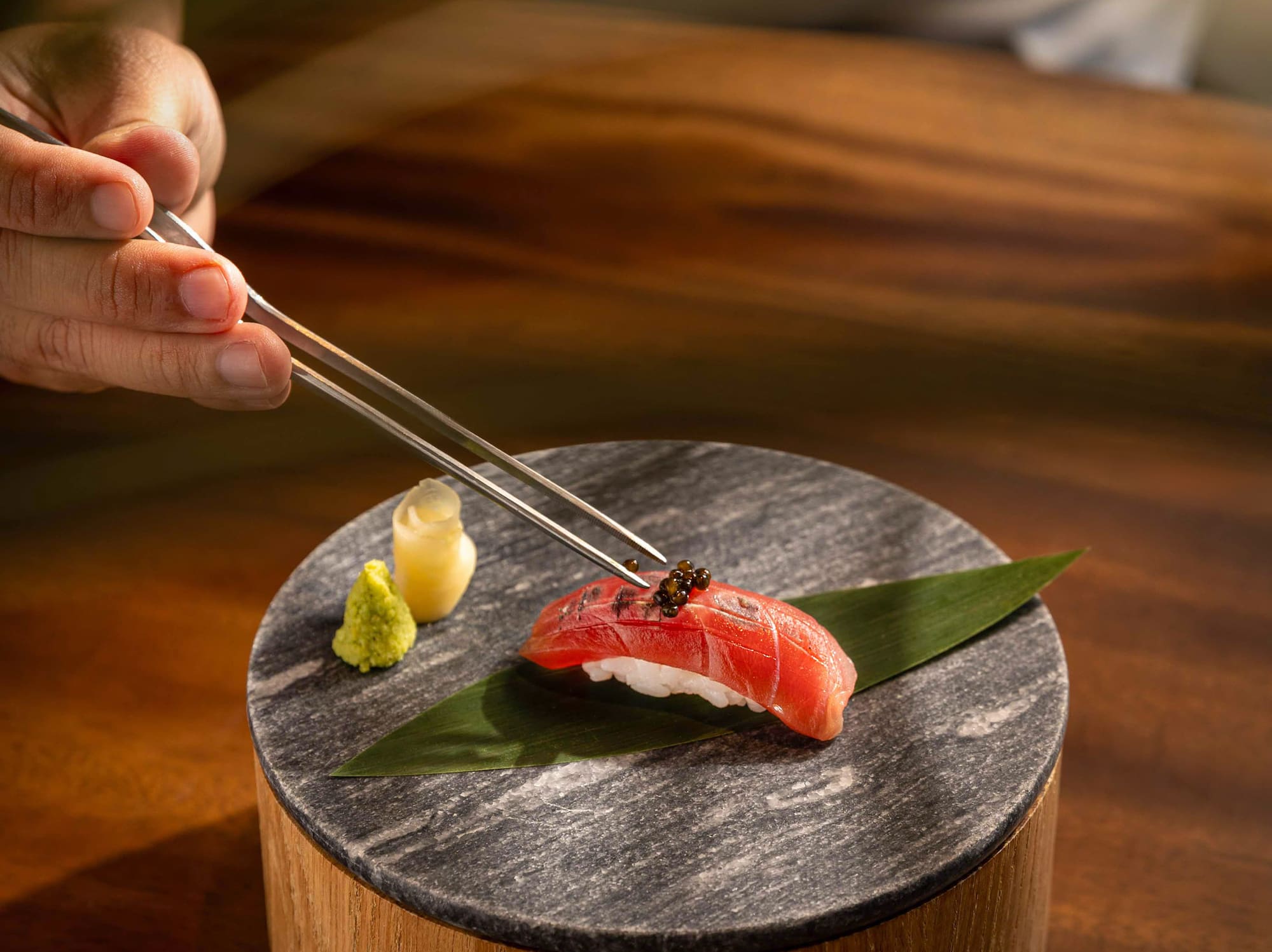 a person holding a piece of sushi