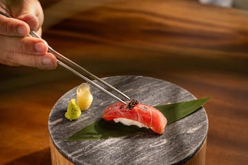 a person holding a piece of sushi