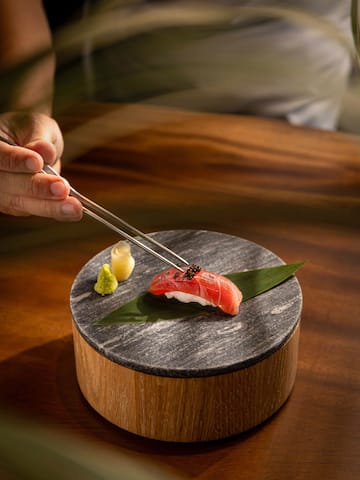 a person holding a piece of sushi