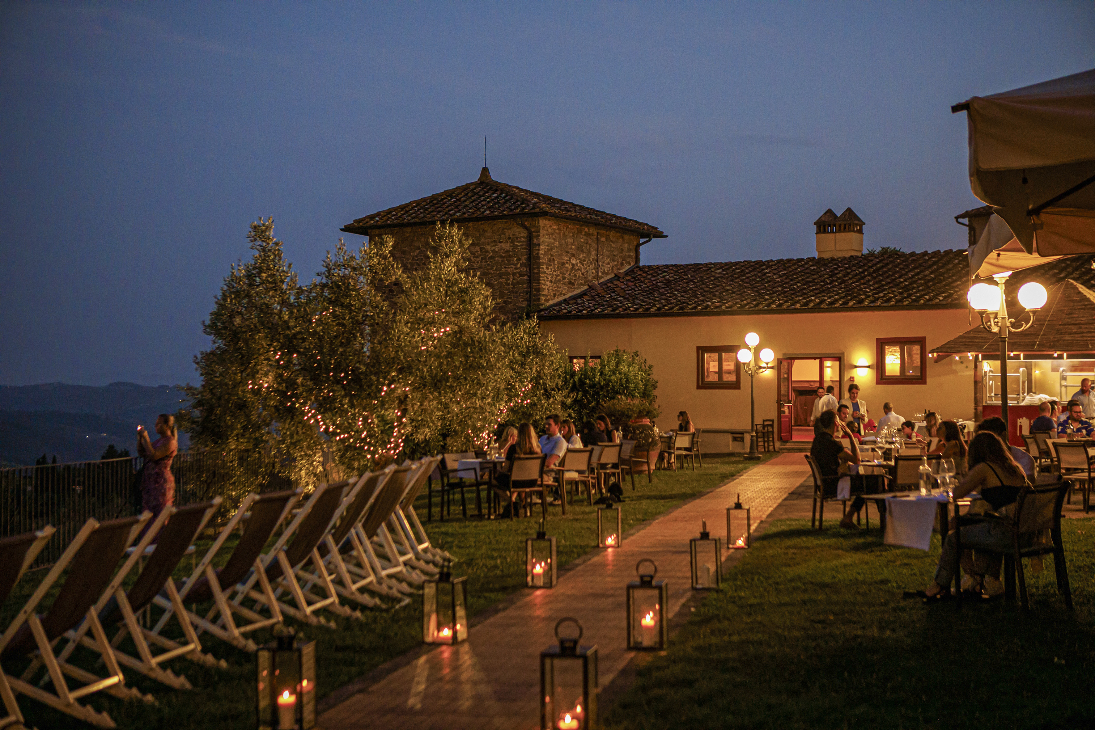 Al fresco dining at a Tuscan restaurant with lanterns at night.