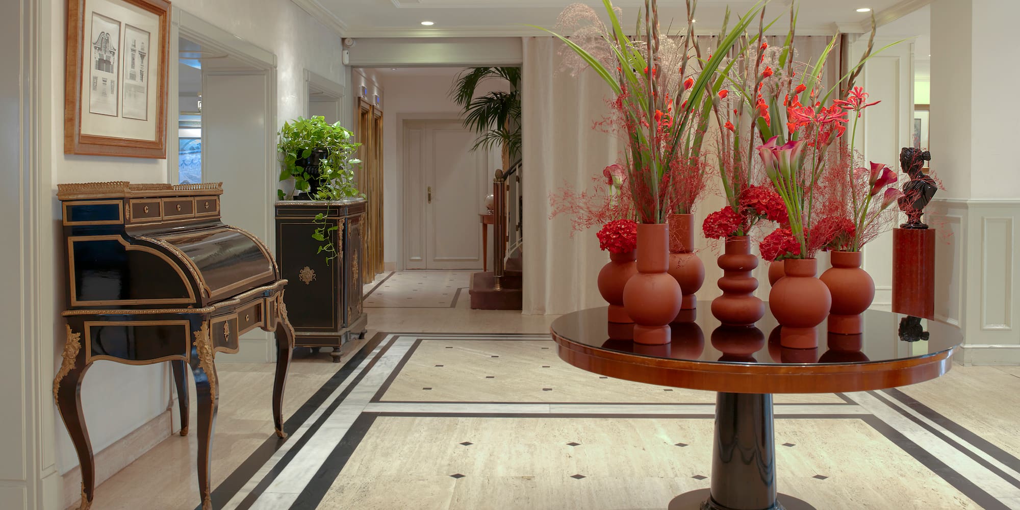 a room with a piano and vases of flowers