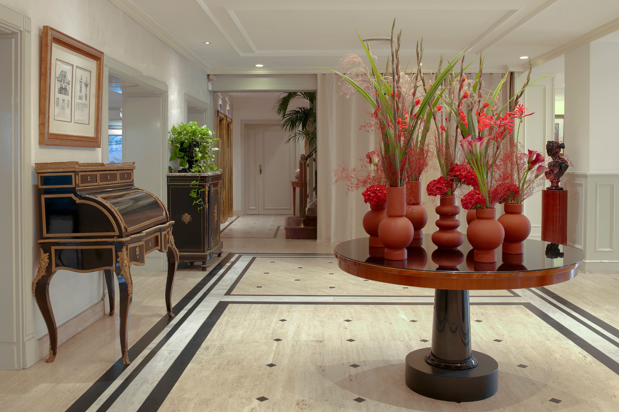 a room with a piano and vases of flowers