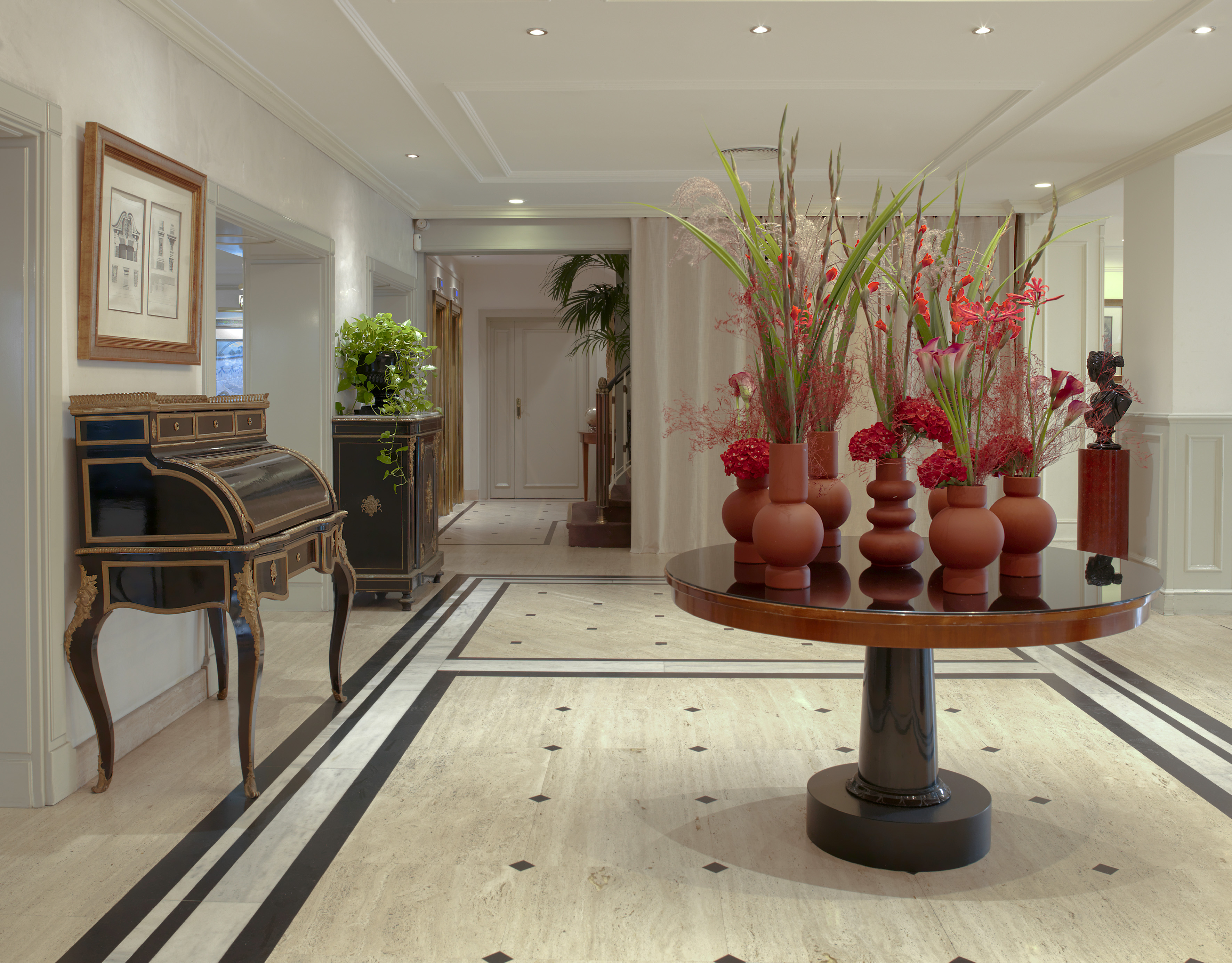 a room with a piano and vases of flowers