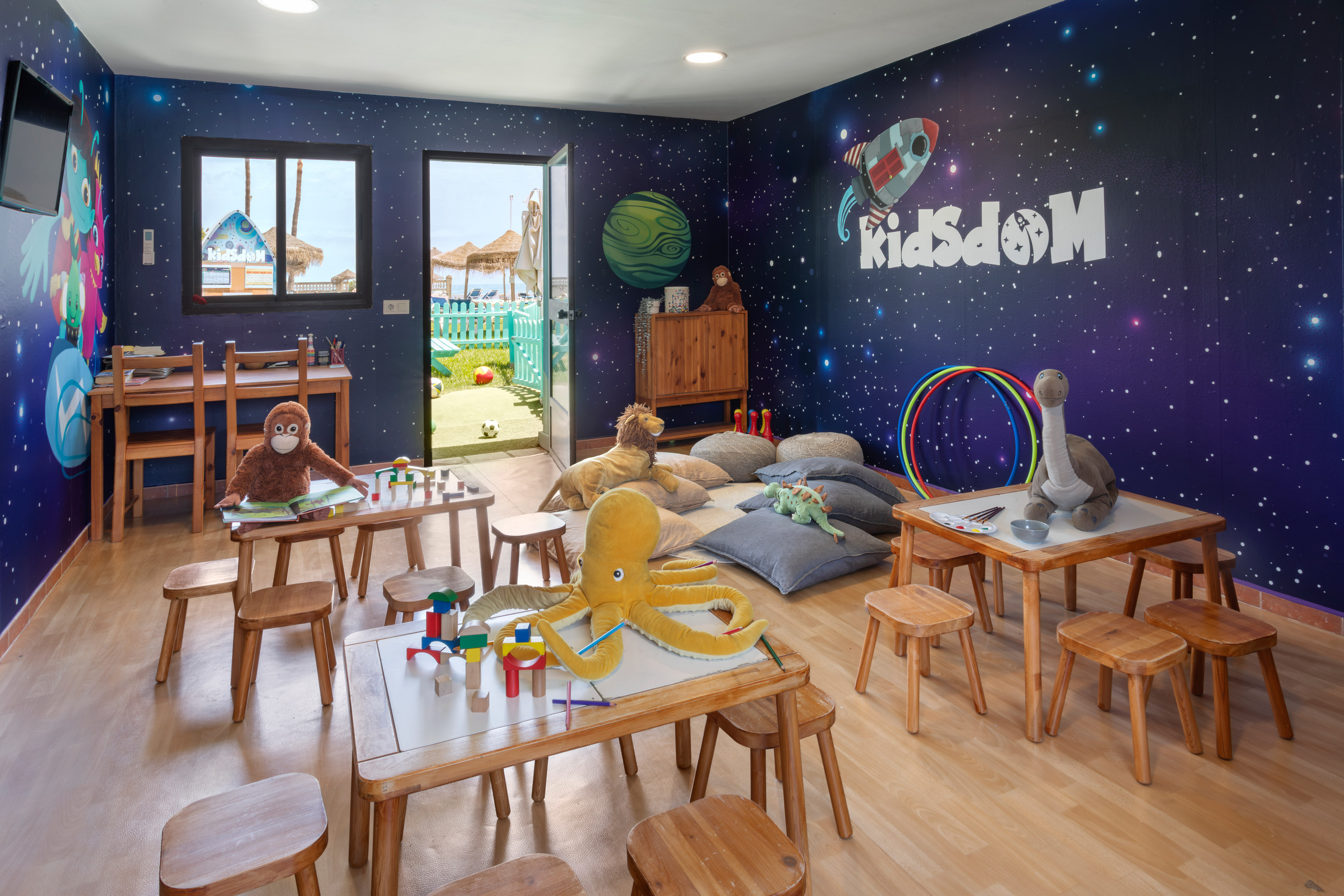 KidsDOM space-themed kids club with toys, activity tables, and beach view.