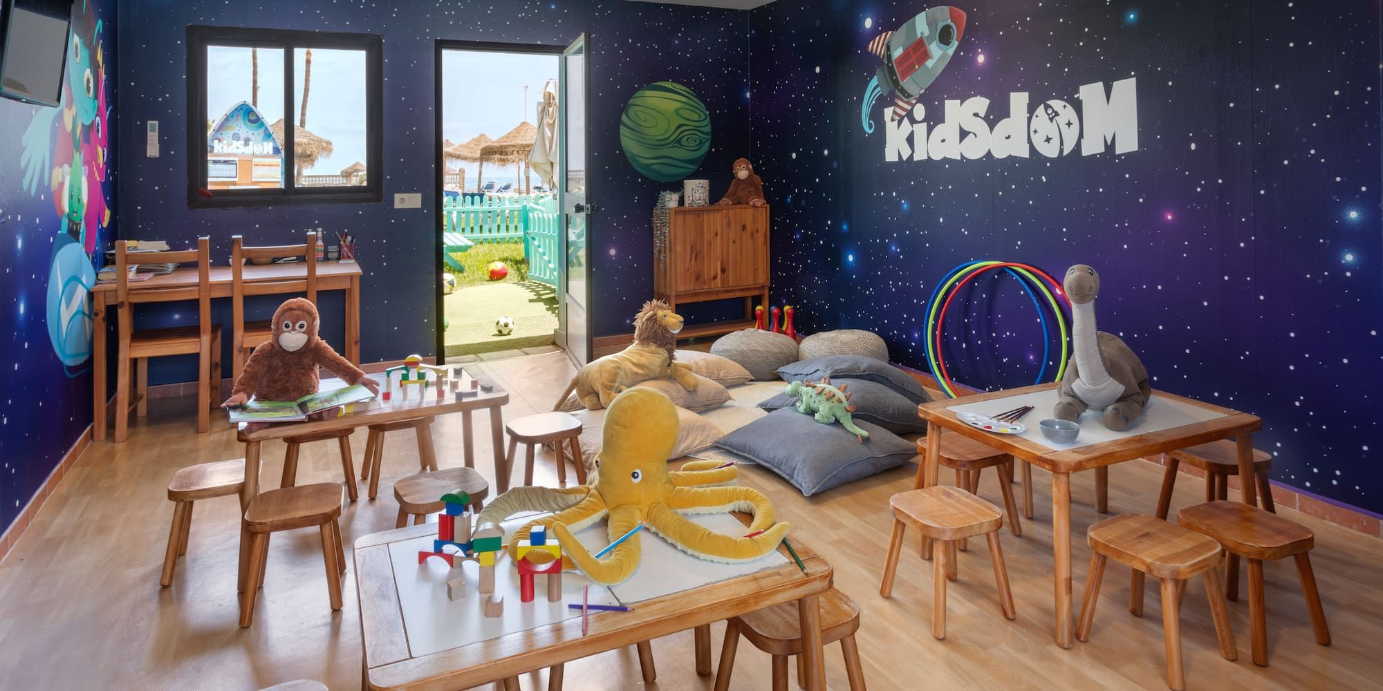 KidsDOM space-themed kids club with toys, activity tables, and beach view.