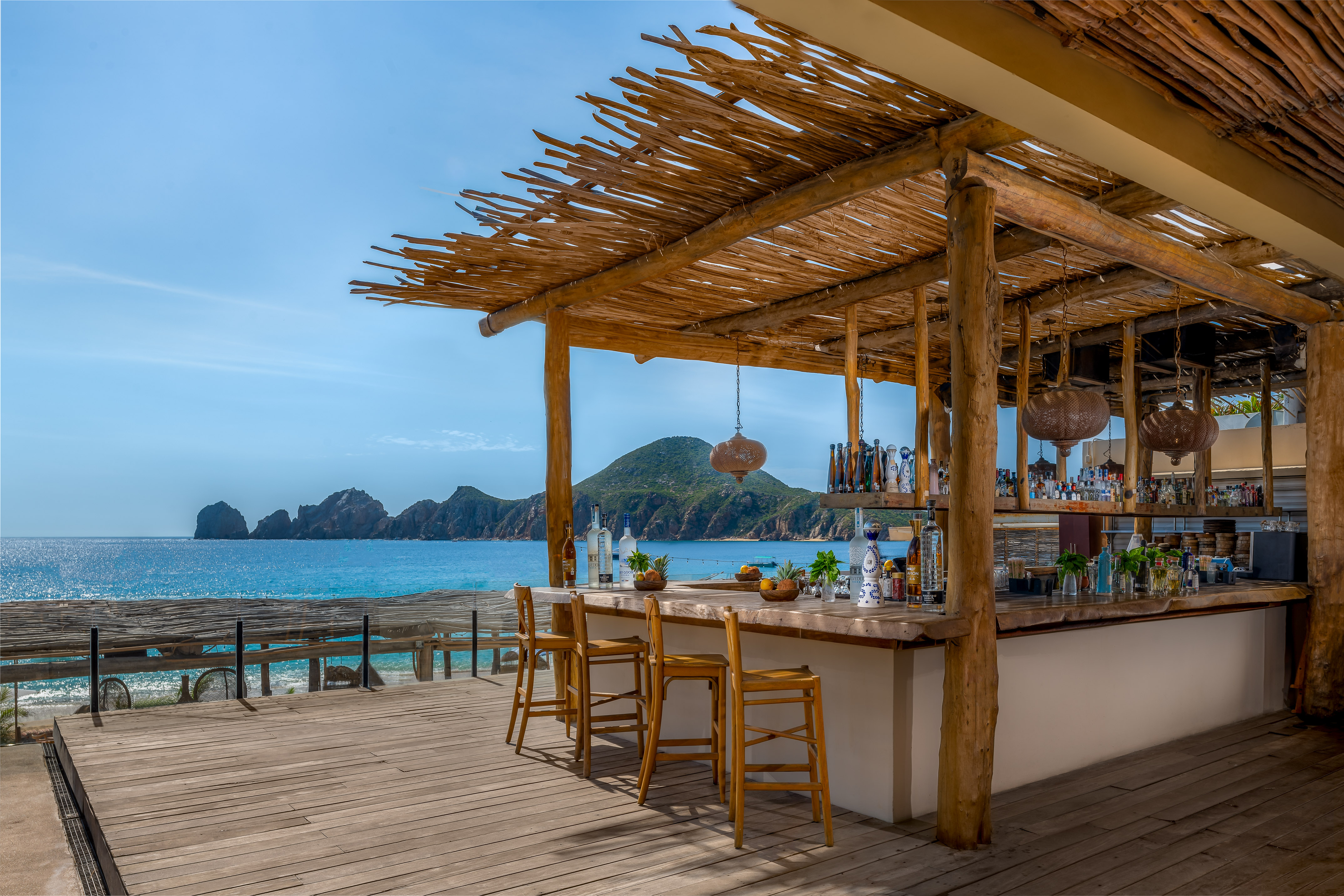 Tropical beach bar with ocean view, wooden deck, and distant islands.
