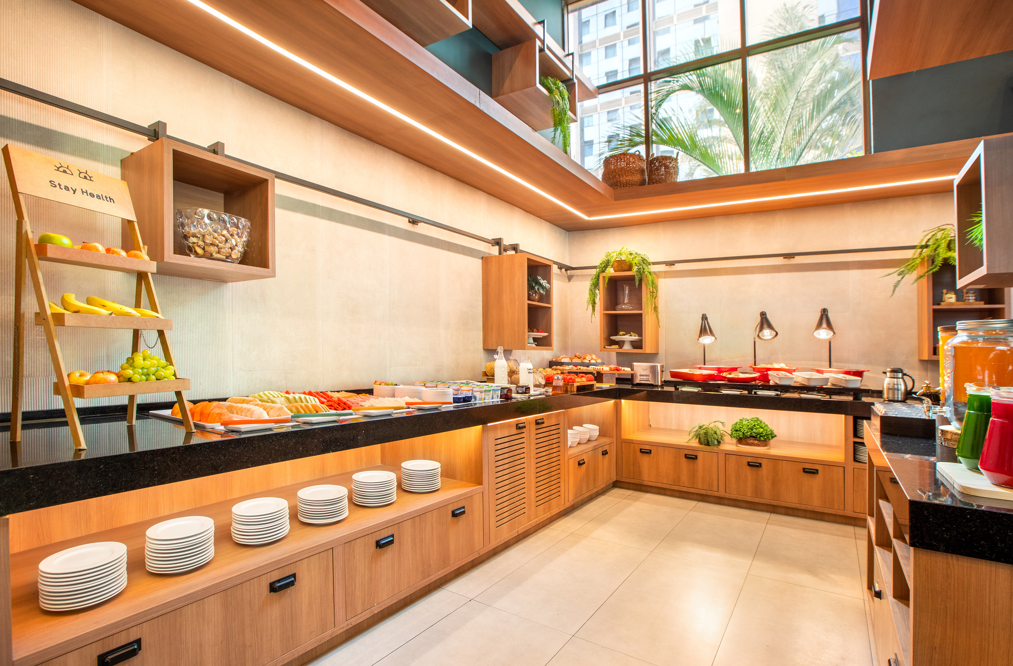 Modern hotel breakfast buffet with fresh fruit, hot food, and juices.