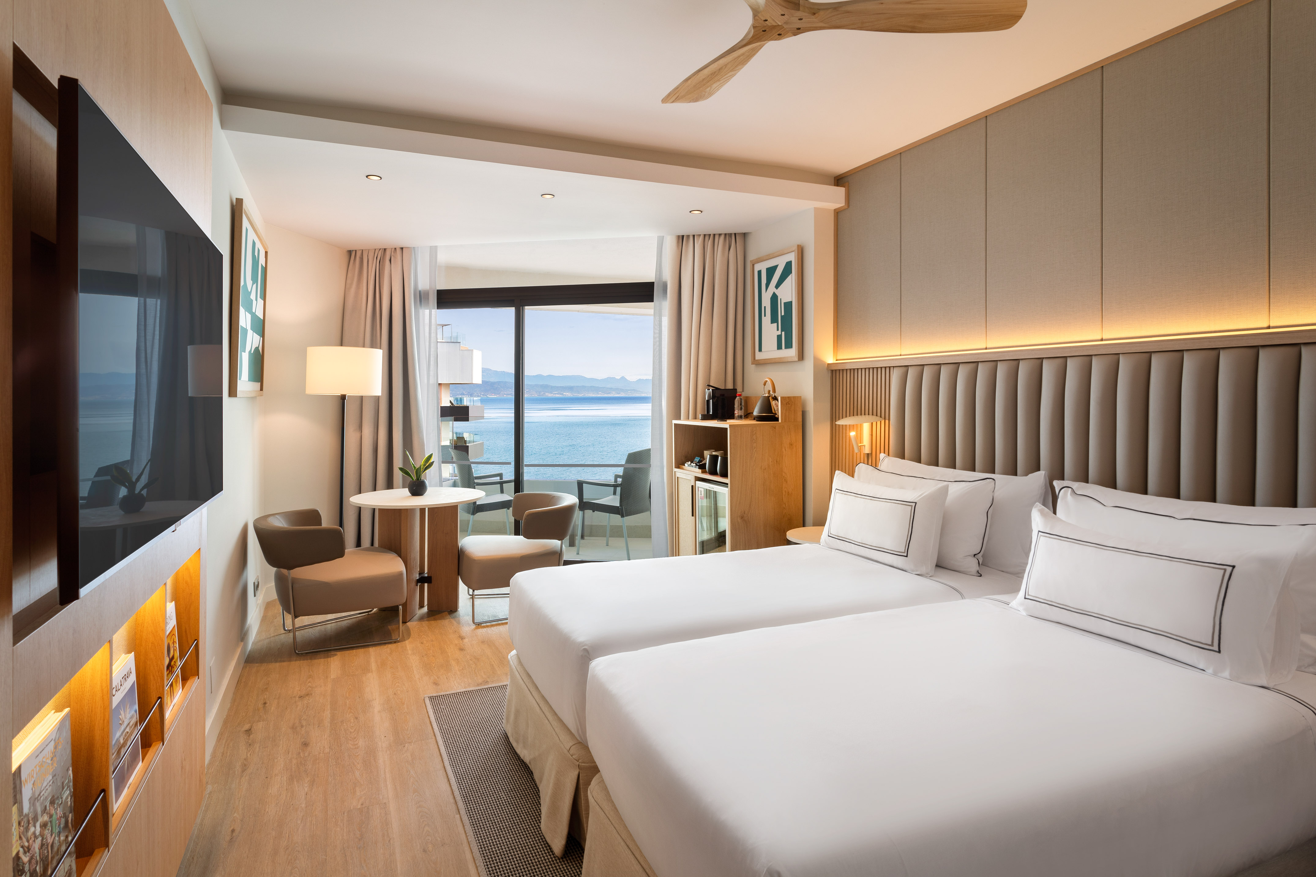 Modern hotel room, twin beds, private balcony with stunning ocean view.