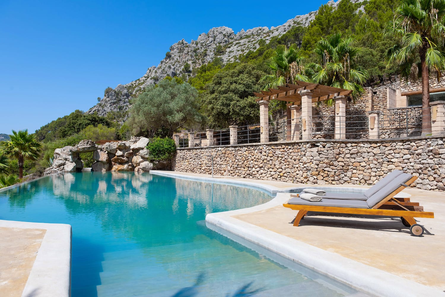 a pool with a stone wall and a stone wall and a stone wall with a stone wall and a stone wall with a stone wall and a stone wall with a stone wall and a stone wall with