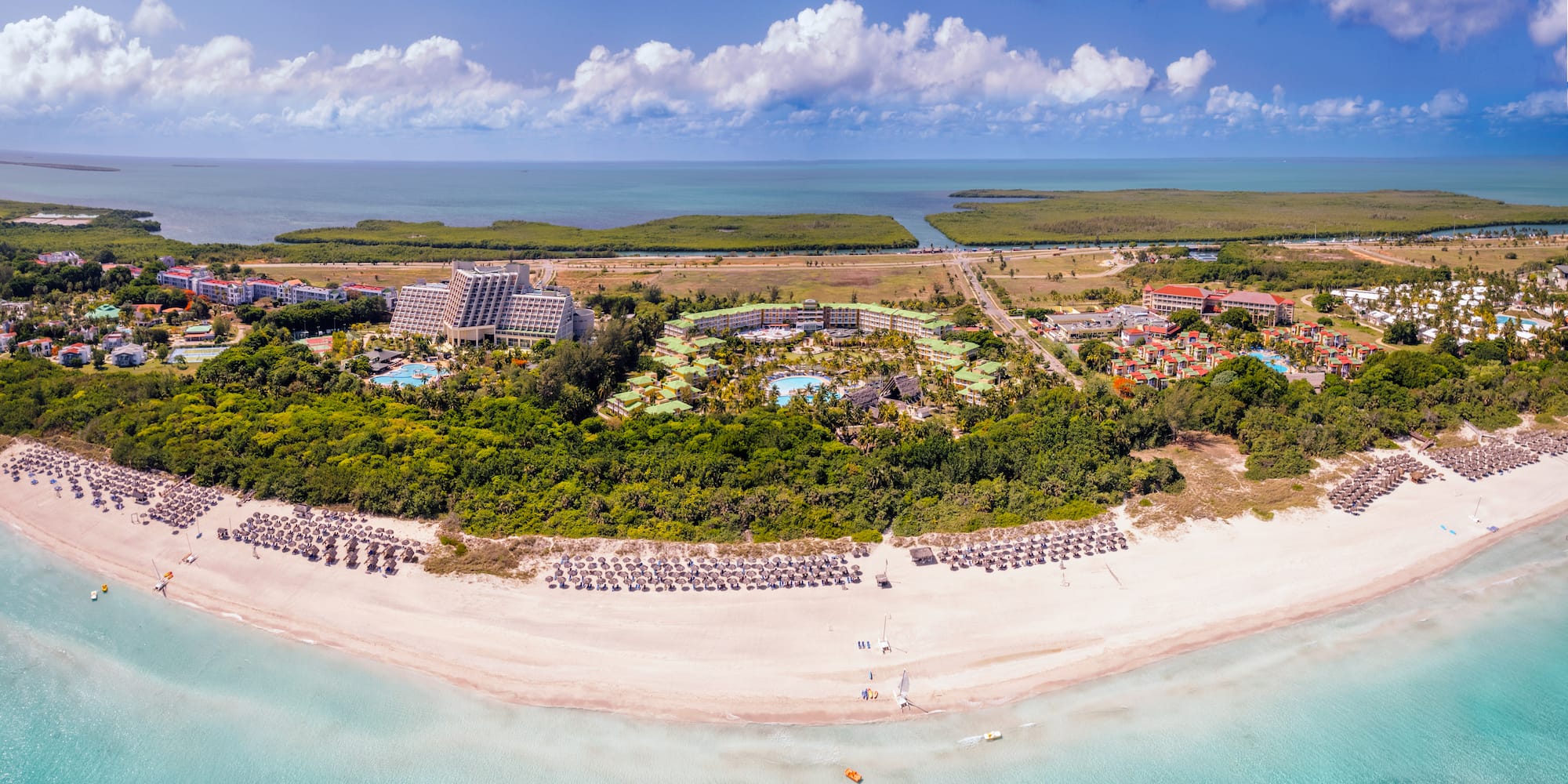 an aerial view of a beach with a pool and trees