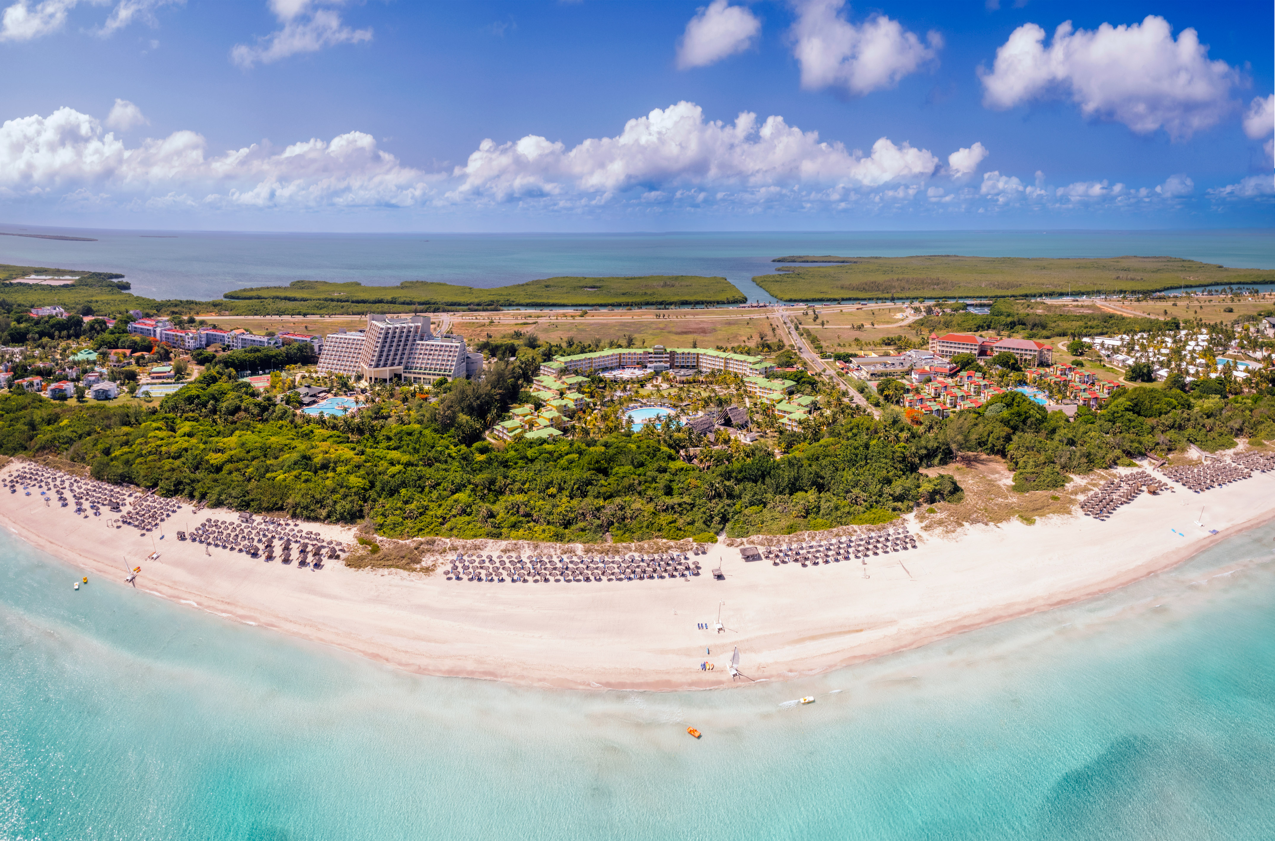 an aerial view of a beach with a pool and trees
