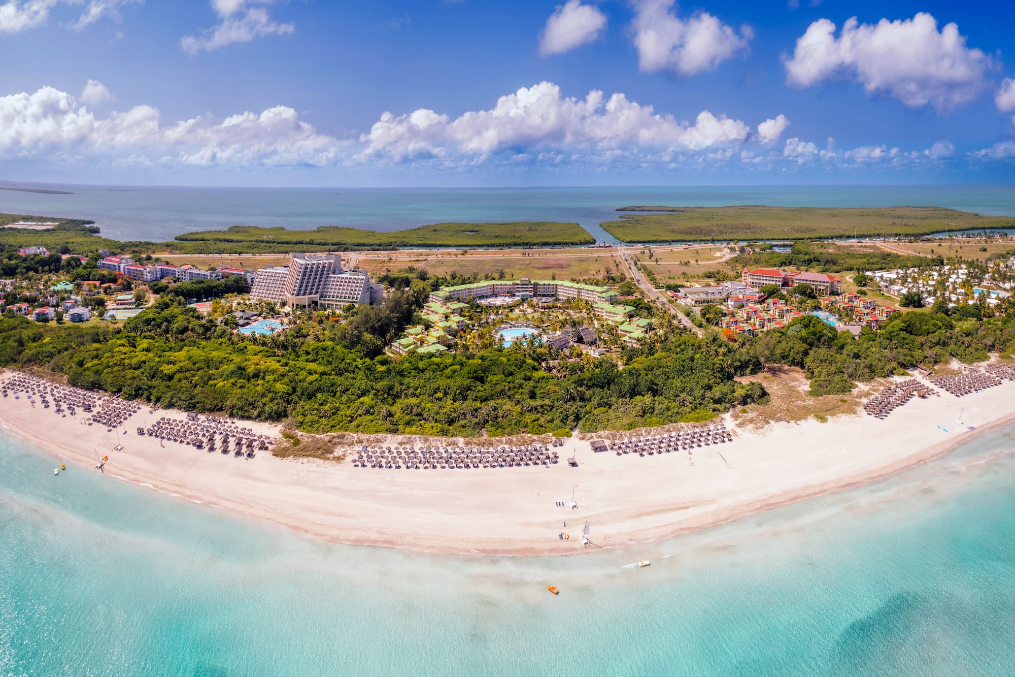 an aerial view of a beach with a pool and trees