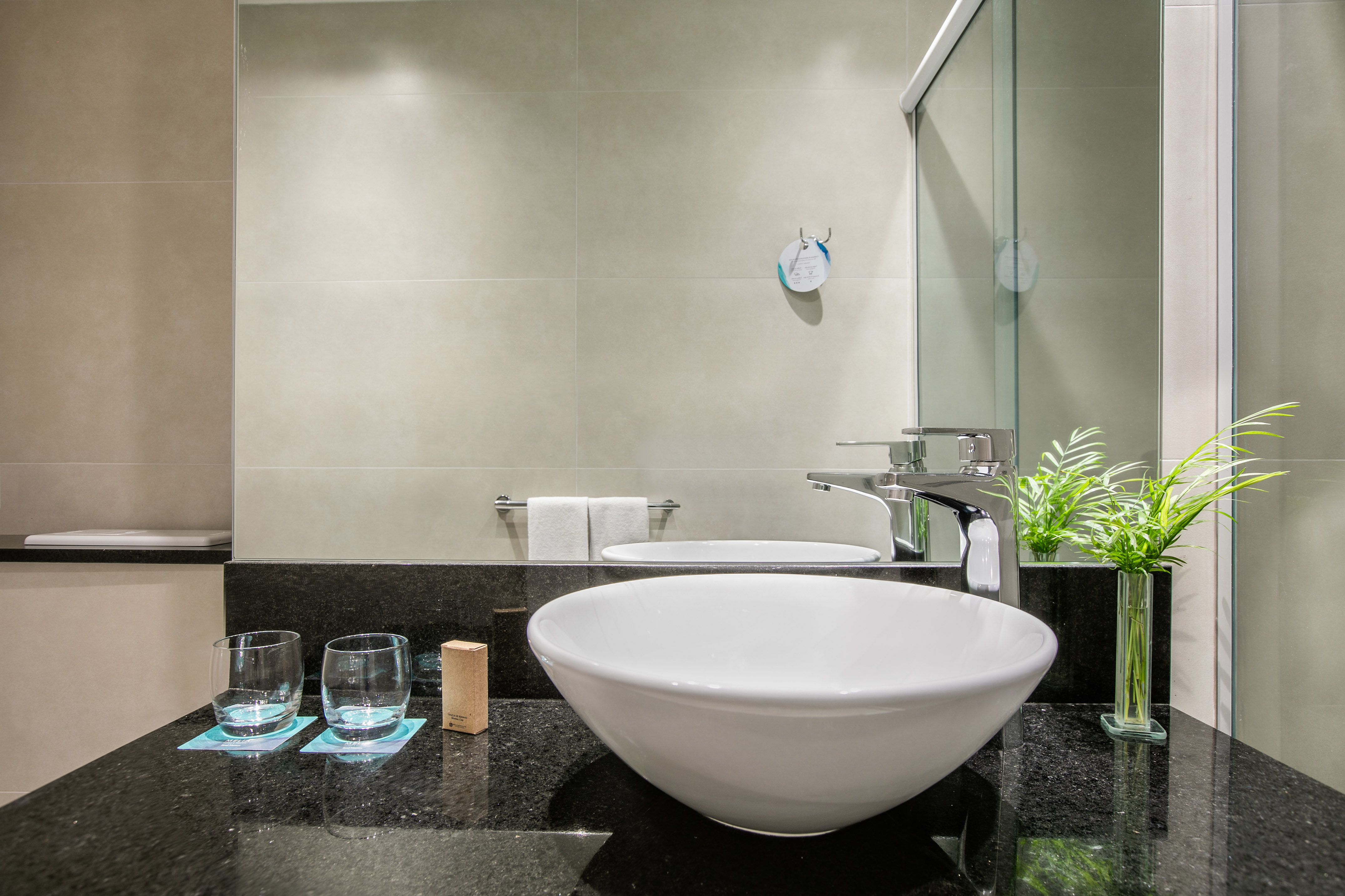 Modern bathroom vanity with white vessel sink, black granite, chrome faucet.