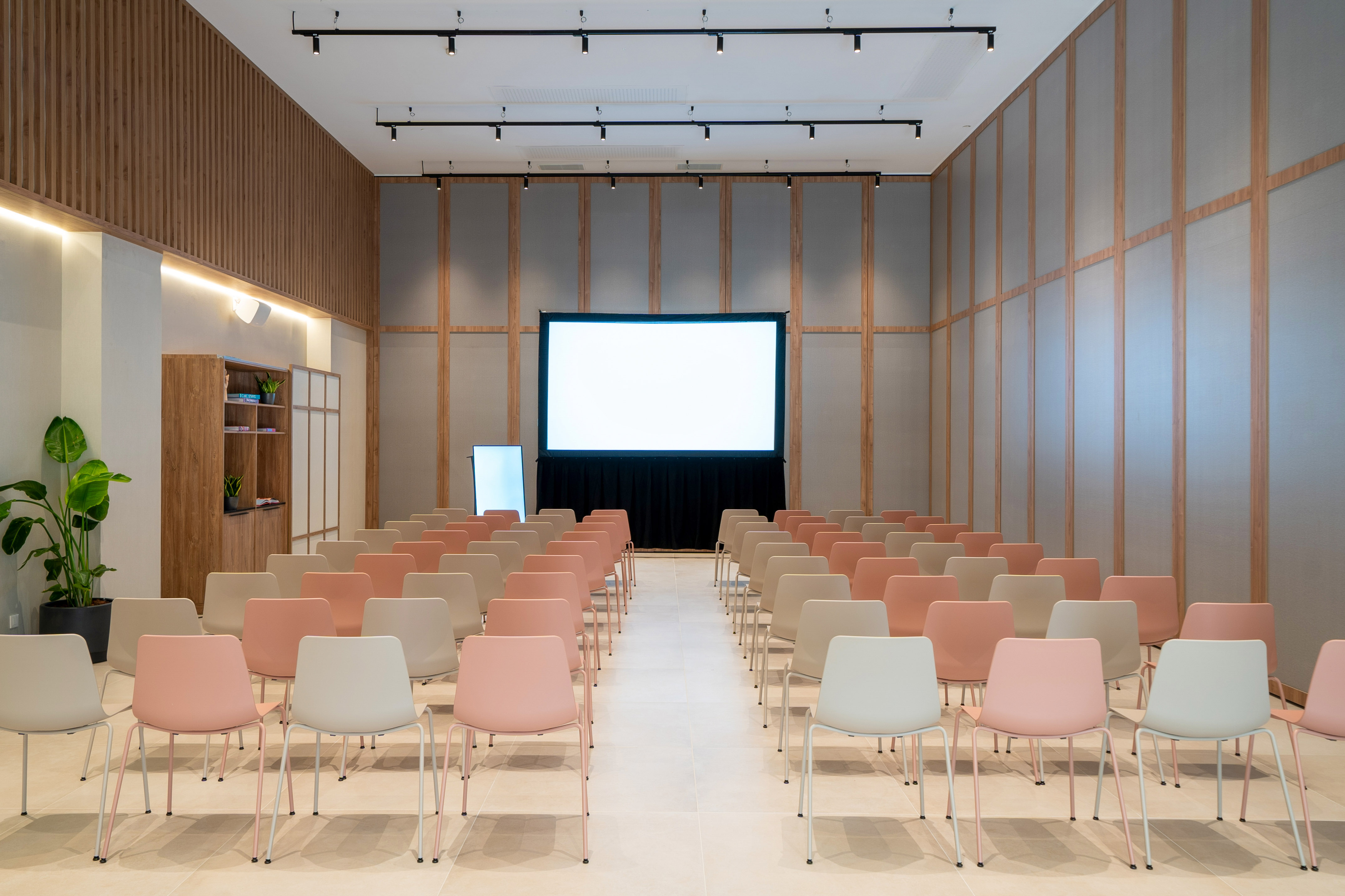 Modern meeting room with projection screen, light chairs, wood paneled walls.