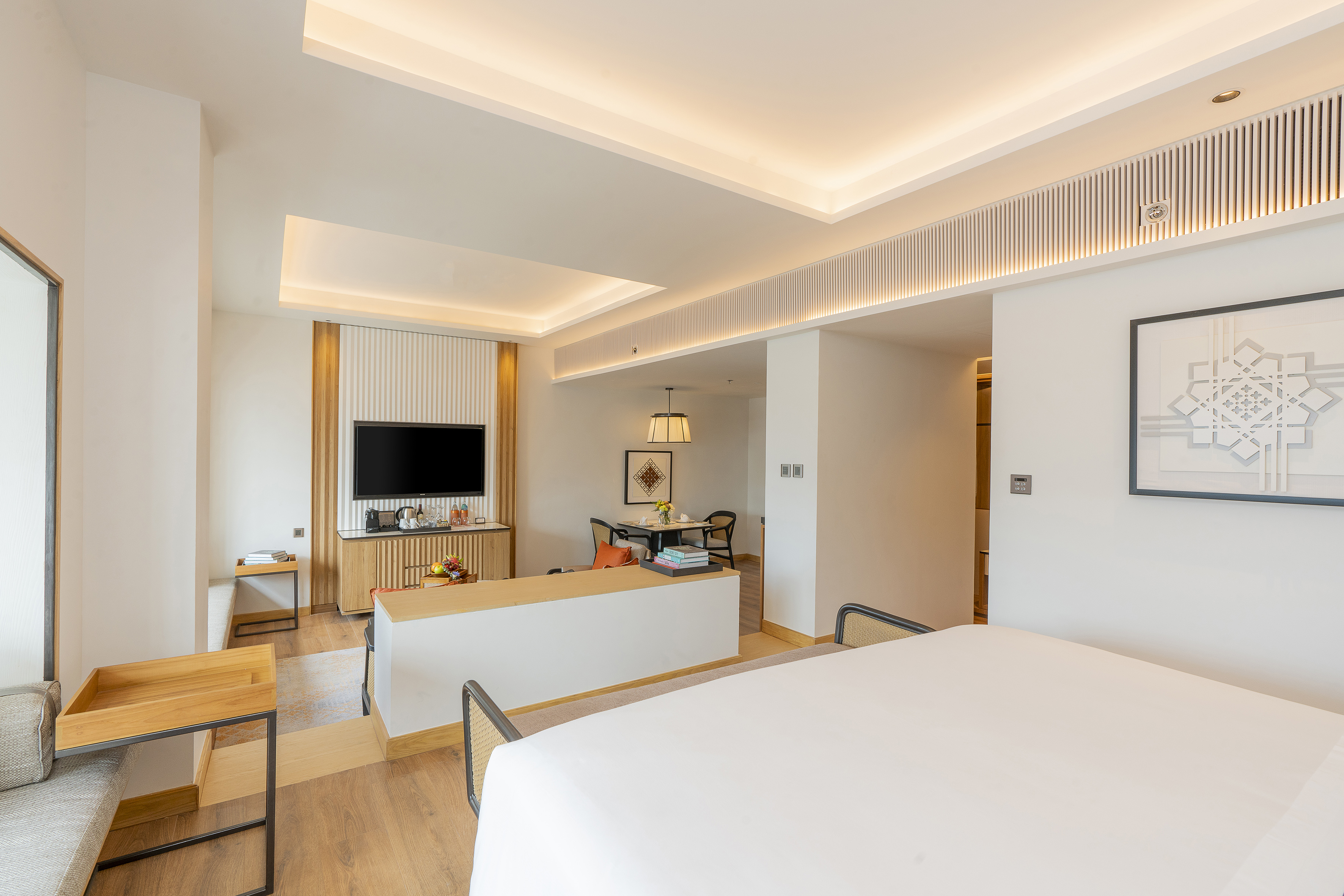 Modern hotel suite with a king bed, TV area, and cozy dining space.