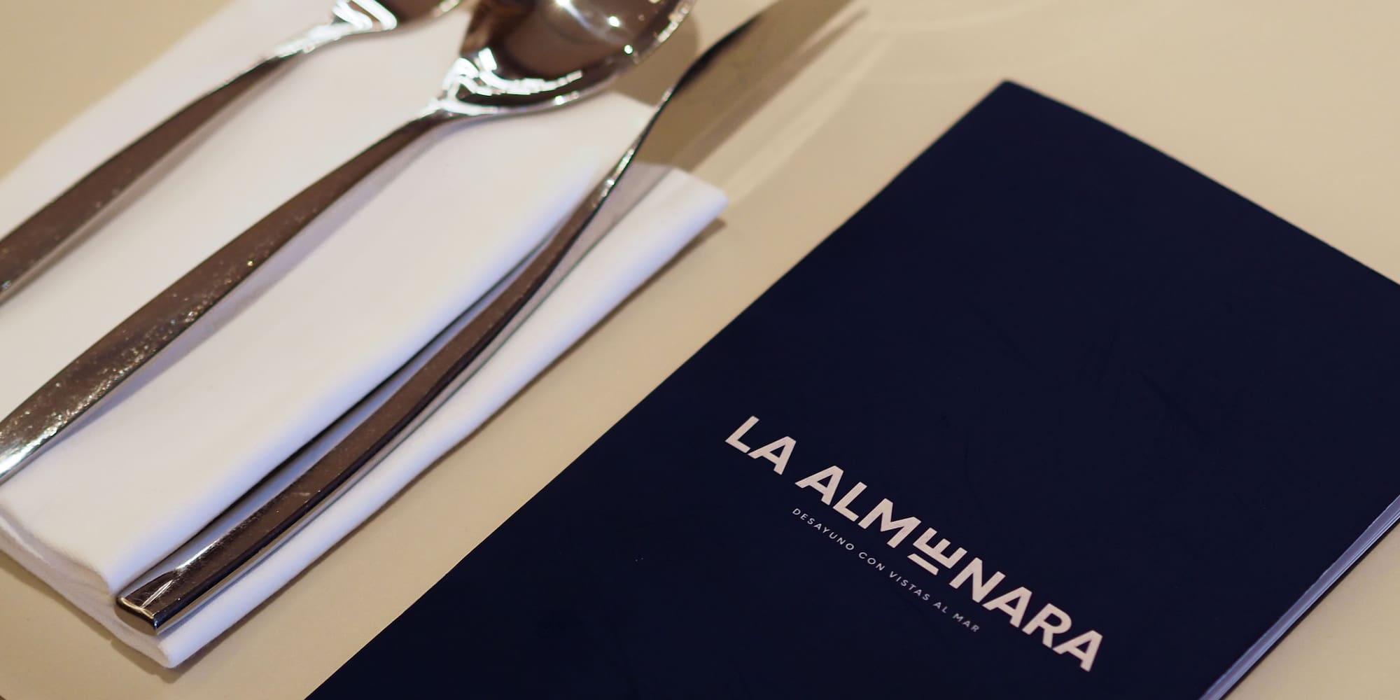 La Almunara restaurant menu, silverware, and glass on a dining table.