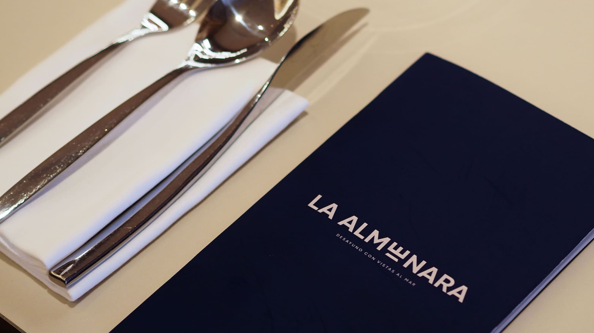 La Almunara restaurant menu, silverware, and glass on a dining table.