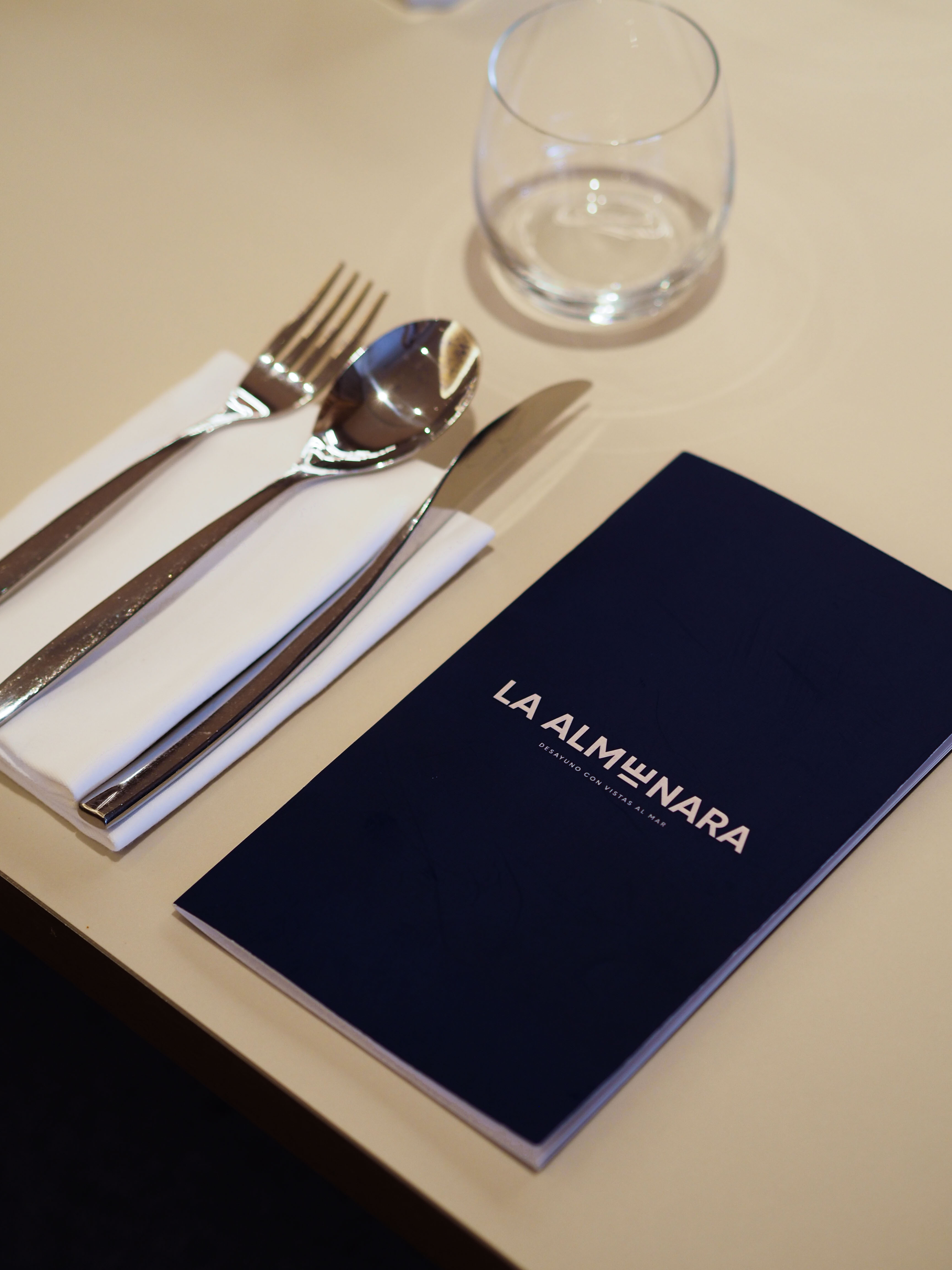 La Almunara restaurant menu, silverware, and glass on a dining table.