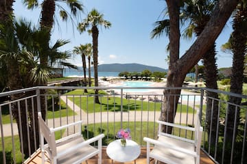 a balcony with a table and chairs and a pool in the background