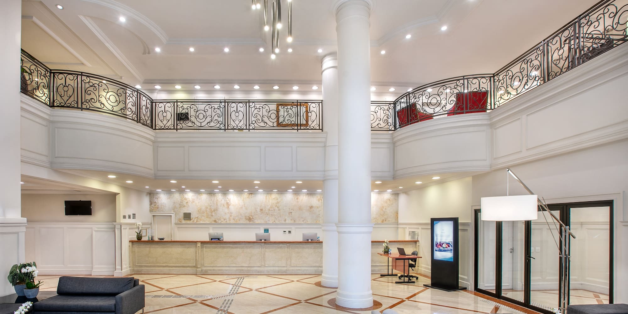 a large white room with a large white column and a large black railing