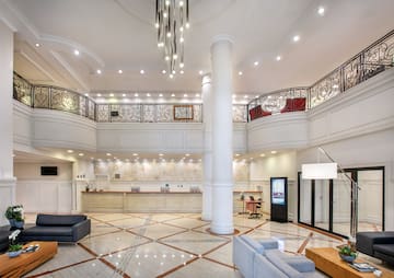 a large white room with a large white column and a large black railing