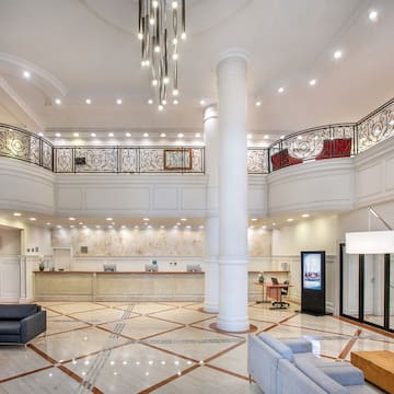 a large white room with a large white column and a large black railing