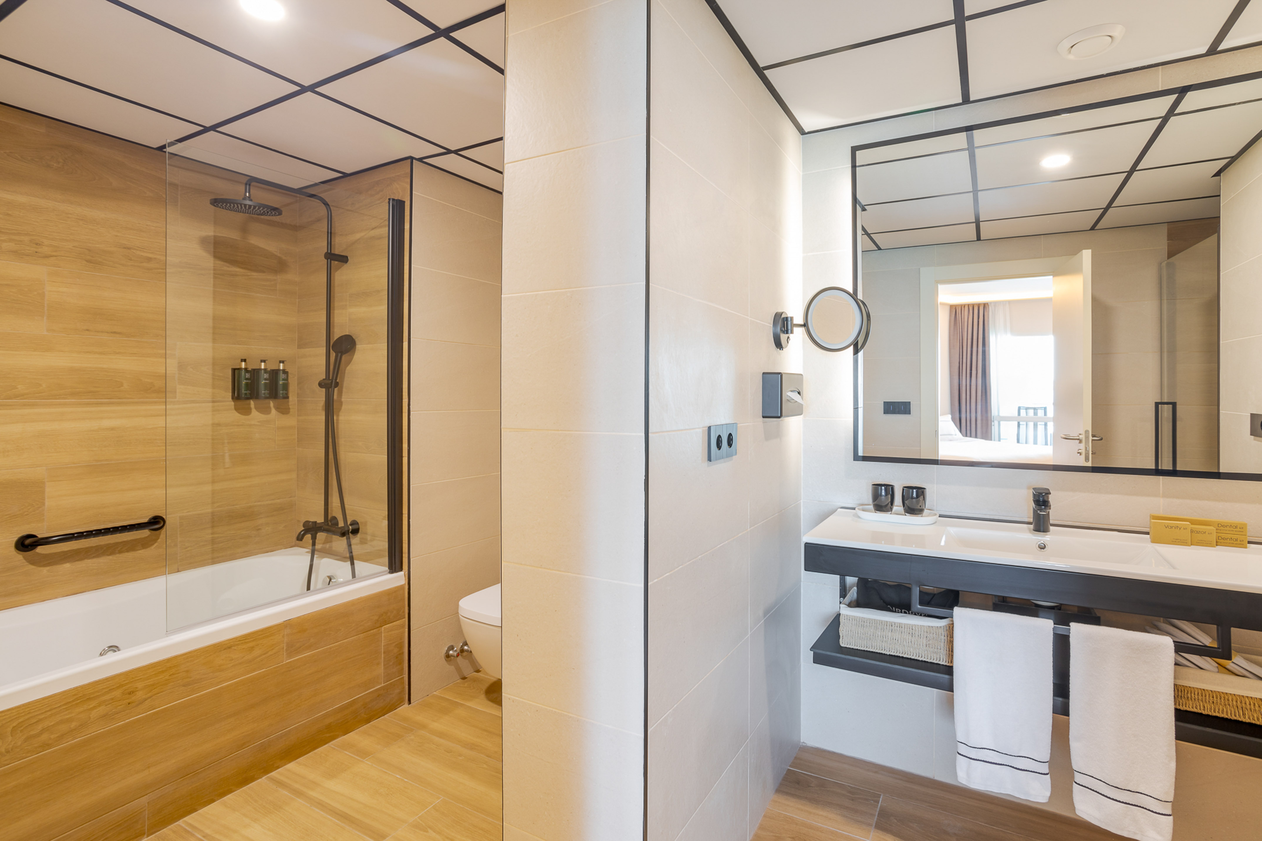 Modern hotel bathroom with shower, bathtub, vanity, and mirror.