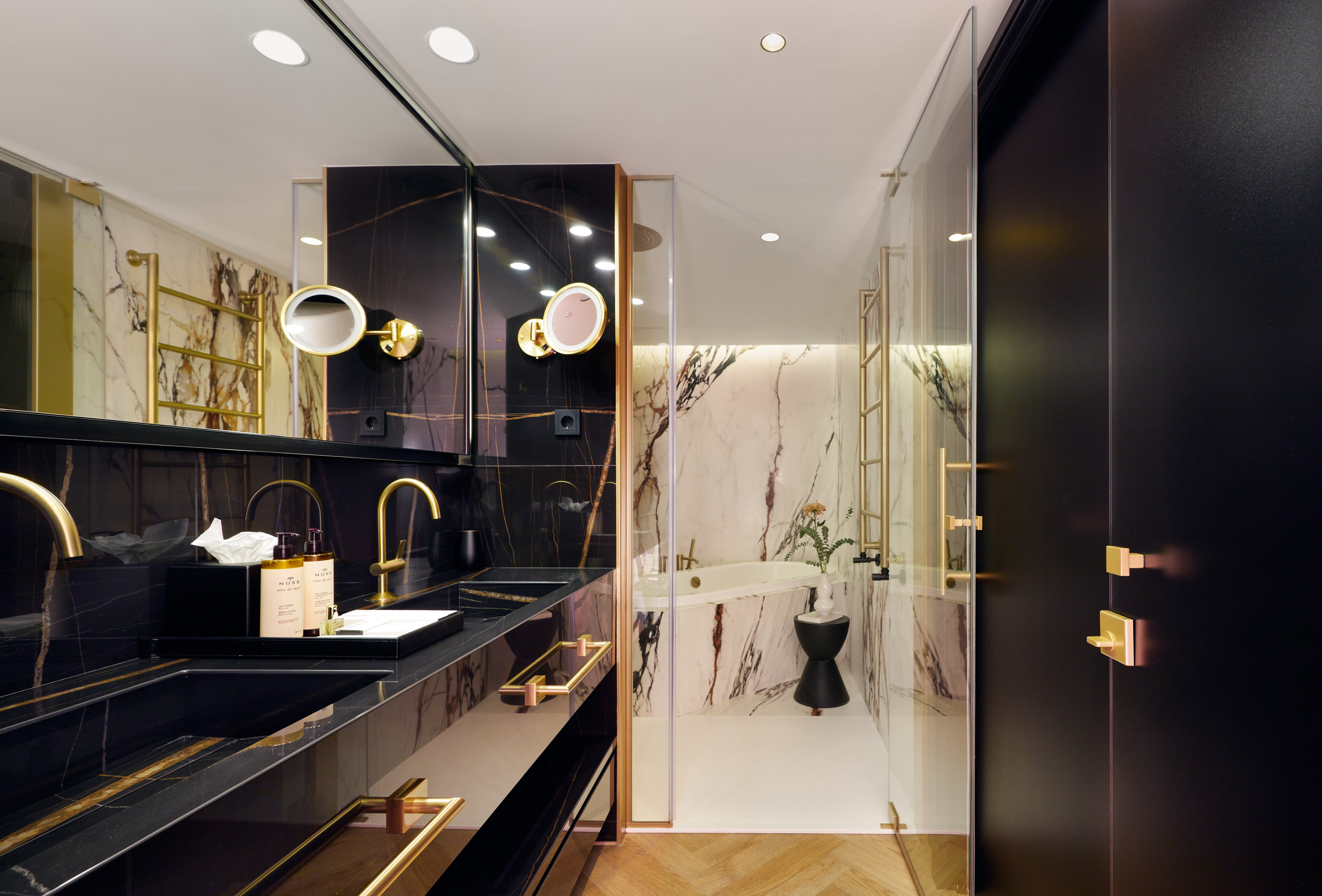 Stylish black and gold marble bathroom with double vanity and bathtub.