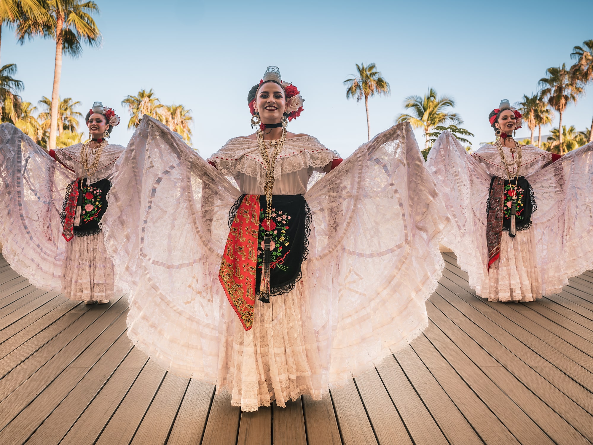 a group of women wearing white dresses and flowers