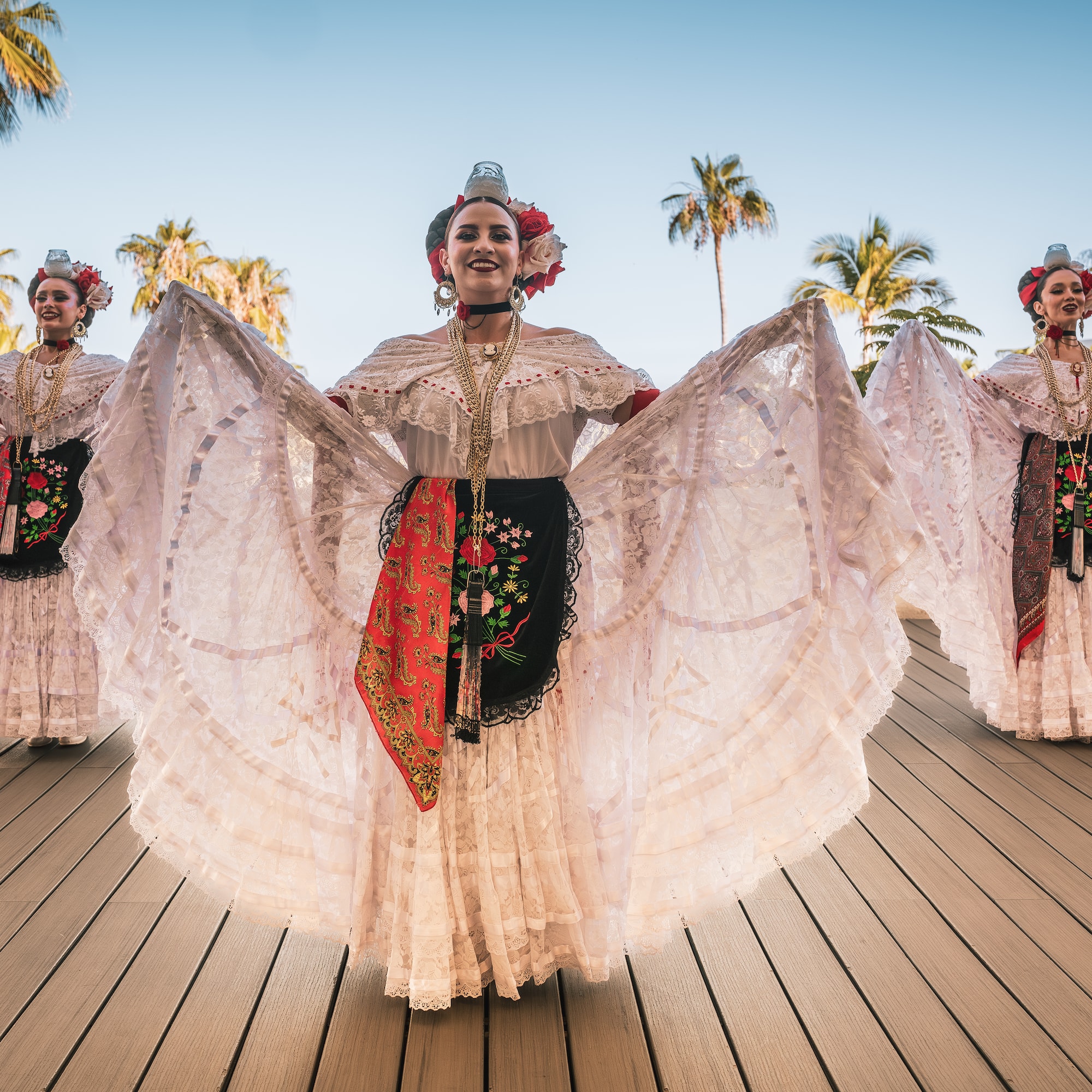 a group of women wearing white dresses and flowers