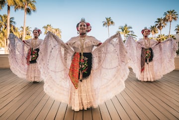 a group of women wearing white dresses and flowers
