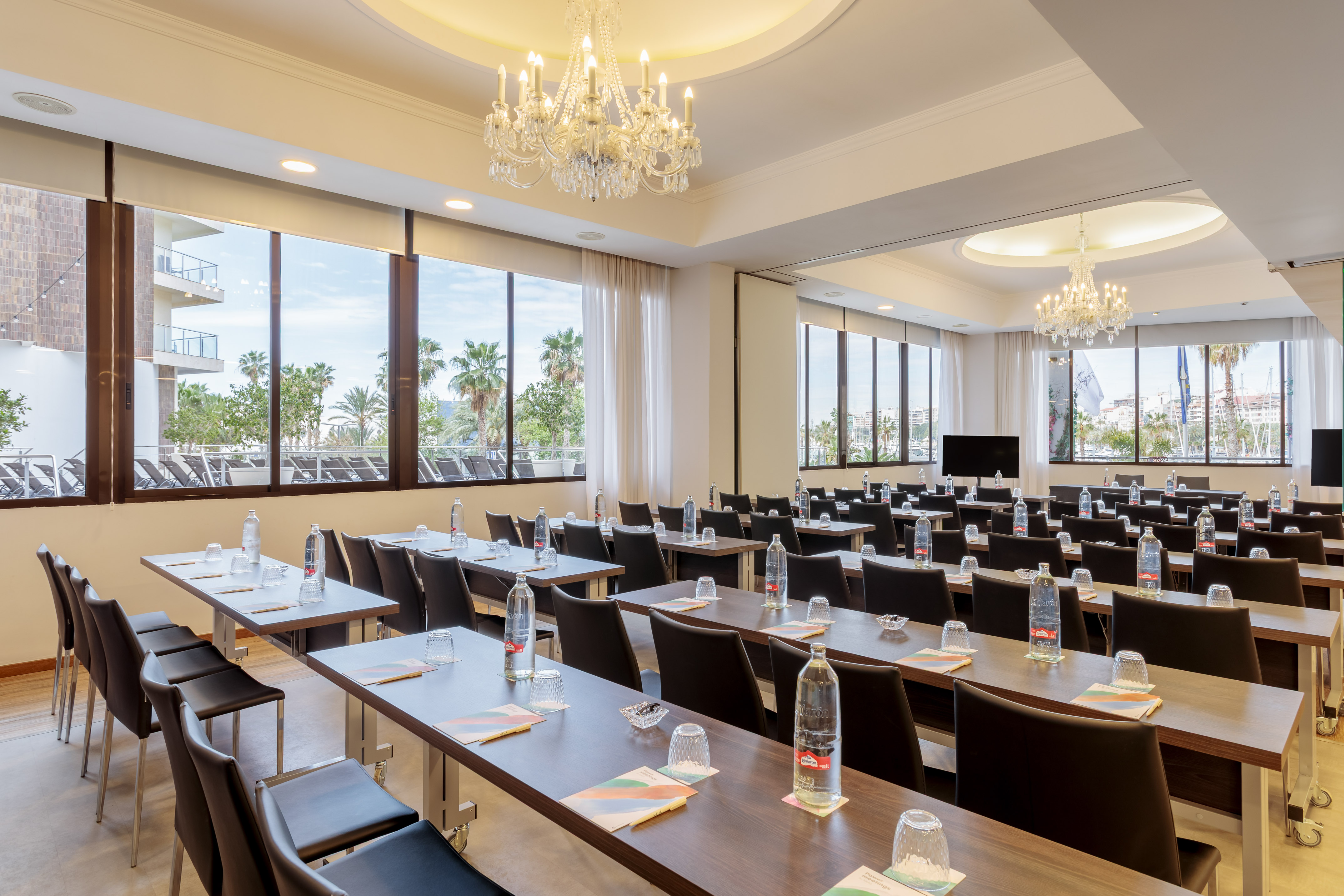 Classroom style conference room with natural light, tables, chairs, and palm tree views.