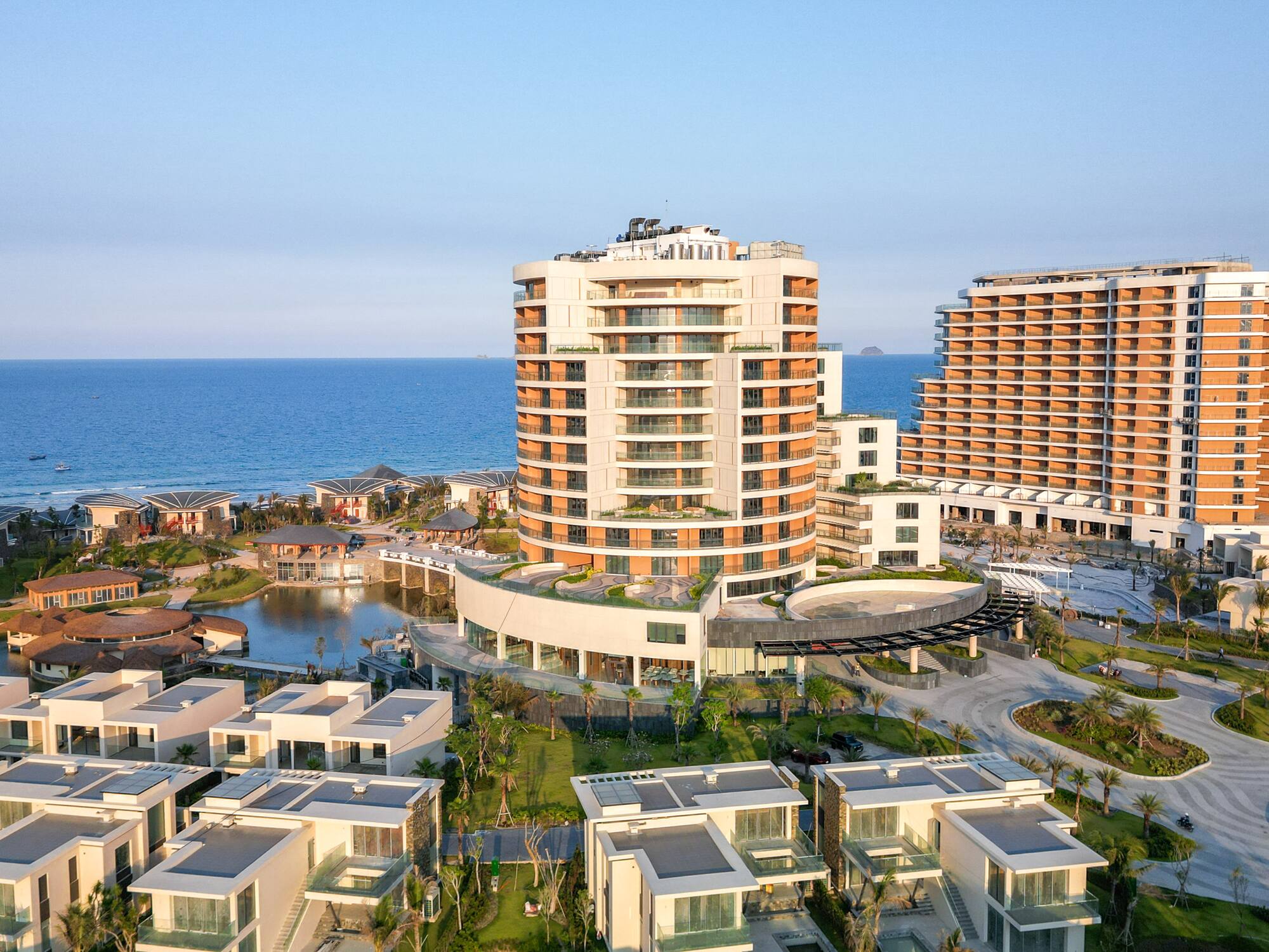 Modern luxury coastal resort complex with high-rise hotels, villas, and ocean.