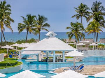 a pool with a white gazebo and palm trees