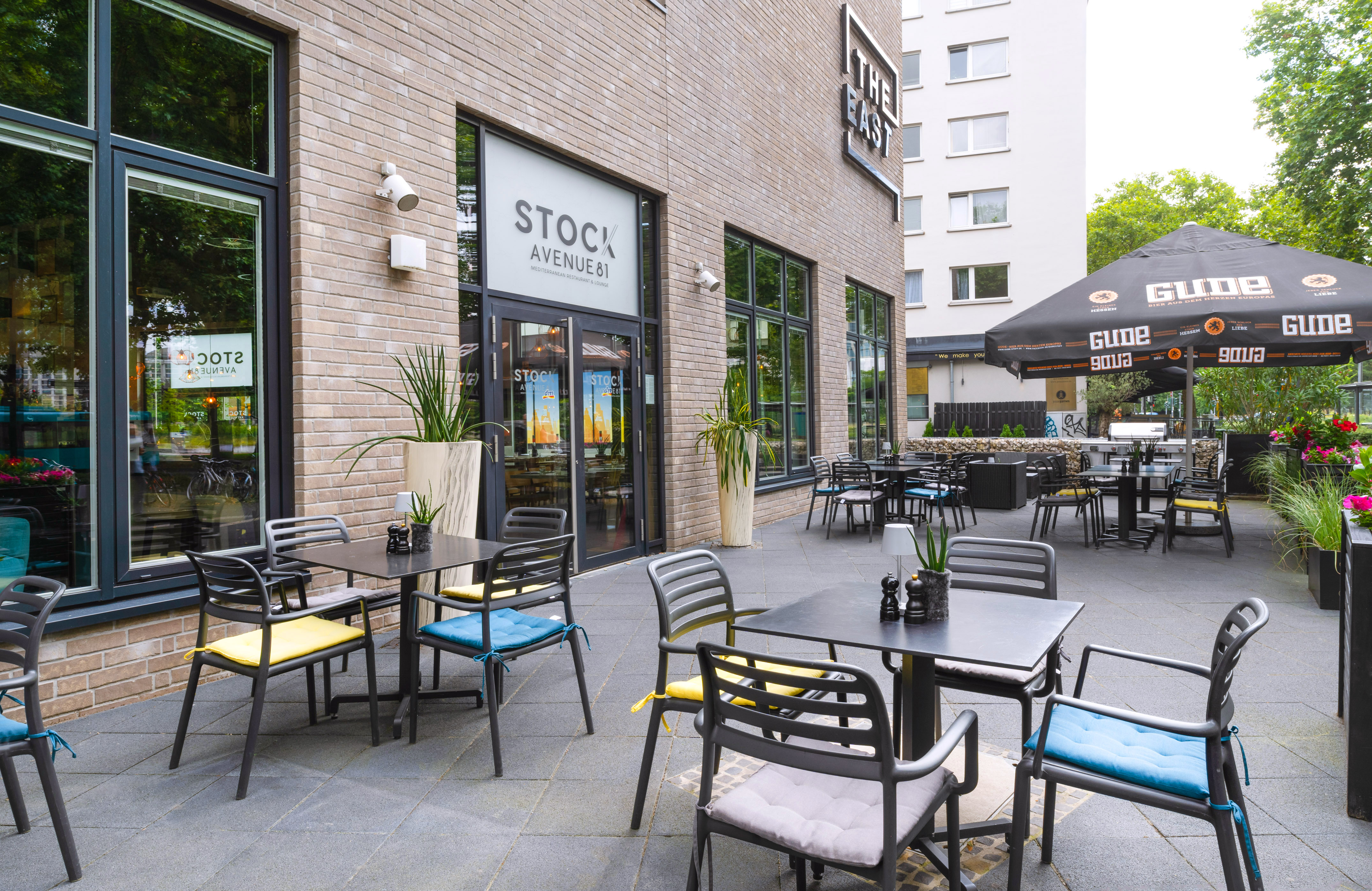 Stock Avenue 81 Mediterranean restaurant patio with tables, chairs, Gude umbrella.