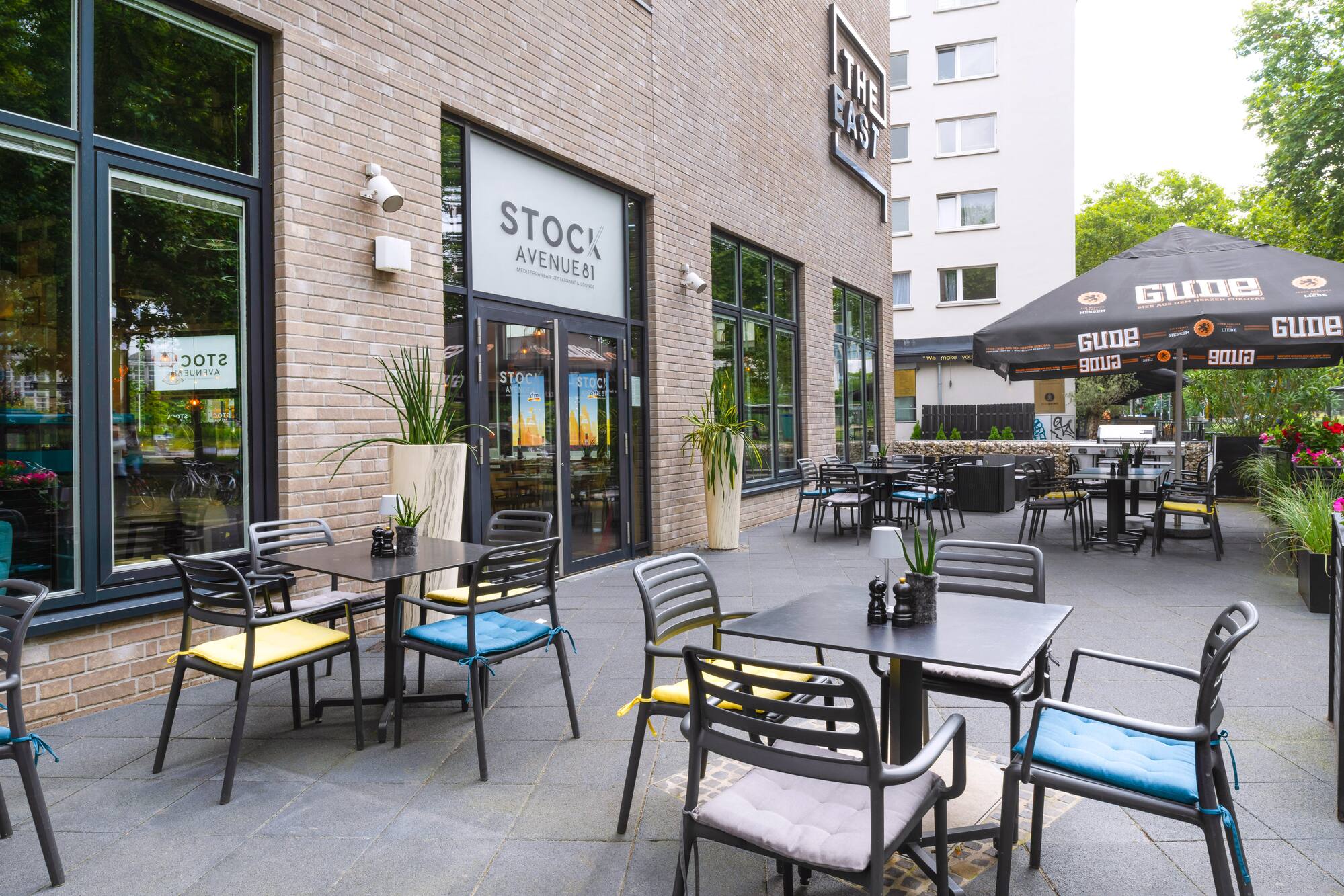 Stock Avenue 81 Mediterranean restaurant patio with tables, chairs, Gude umbrella.