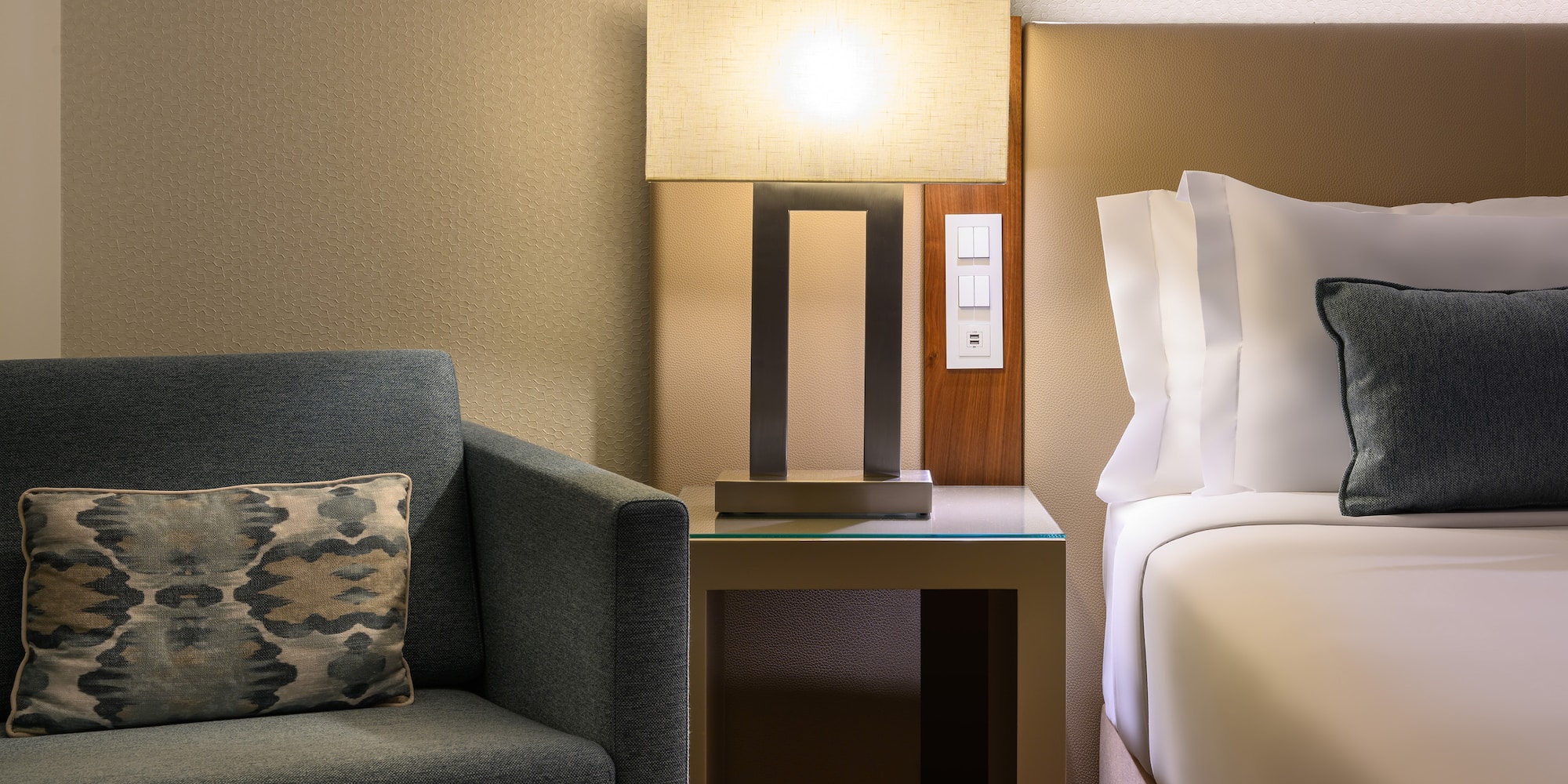 a lamp on a table next to a bed