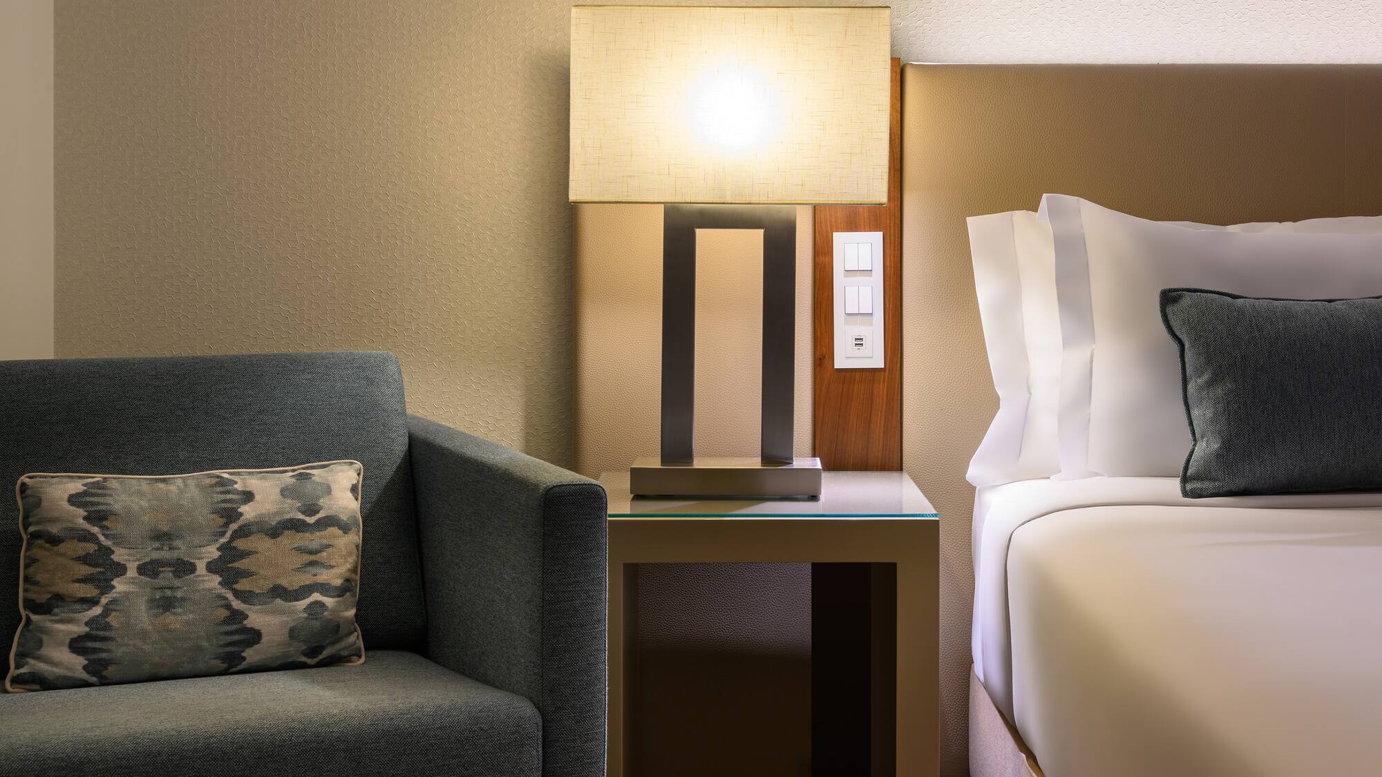 a lamp on a table next to a bed