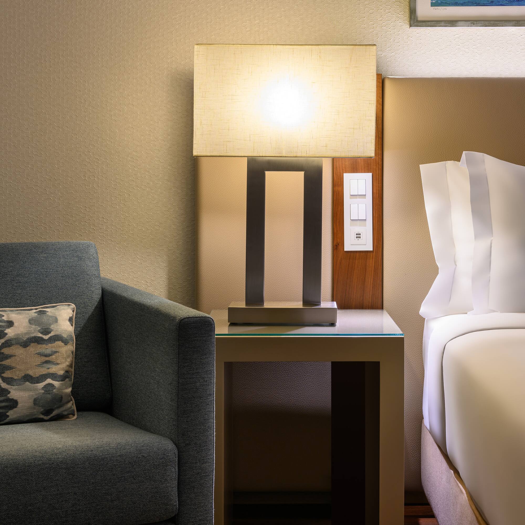 a lamp on a table next to a bed