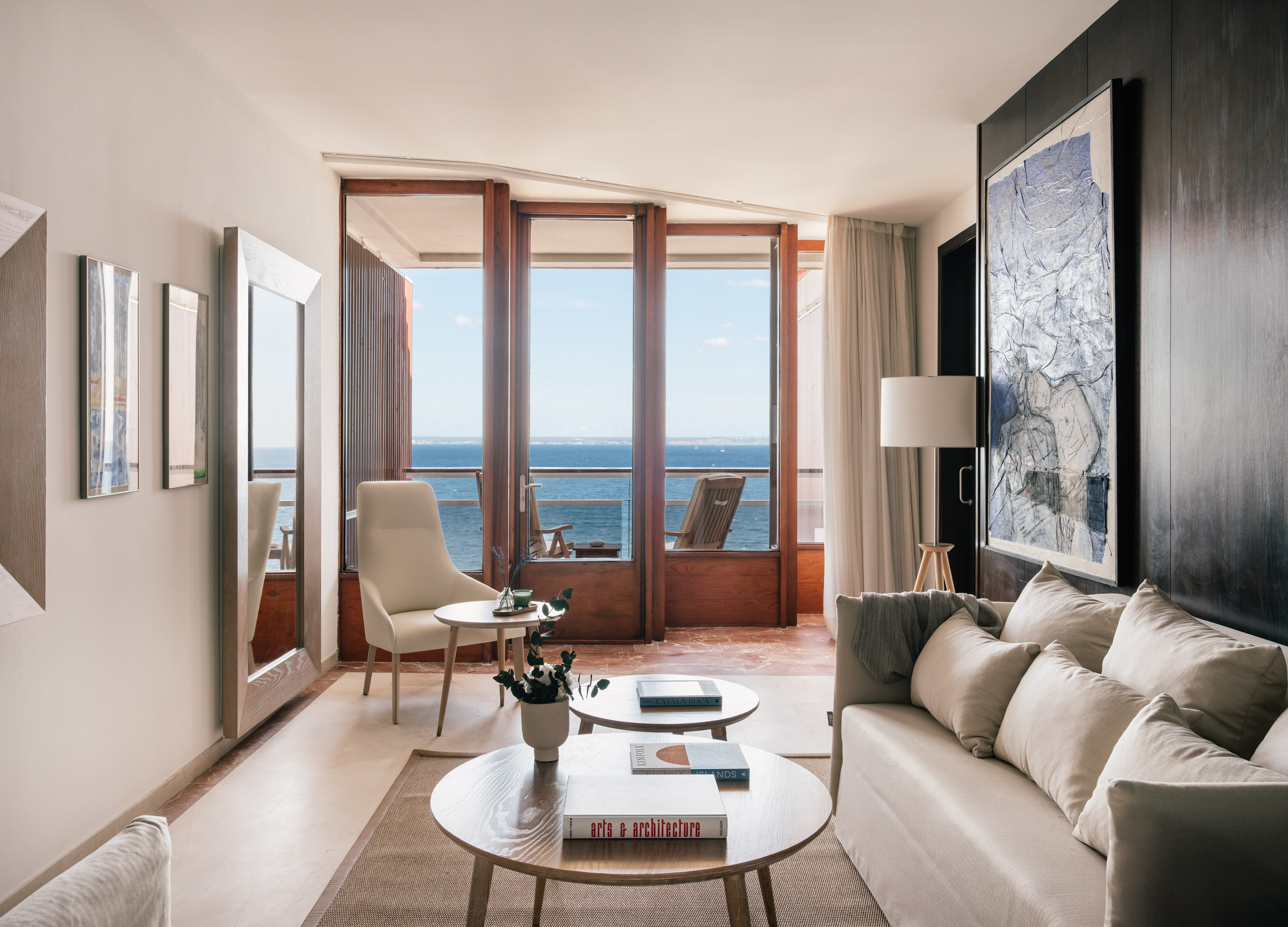 Coastal living room with sea view, sofa, balcony, and modern decor.