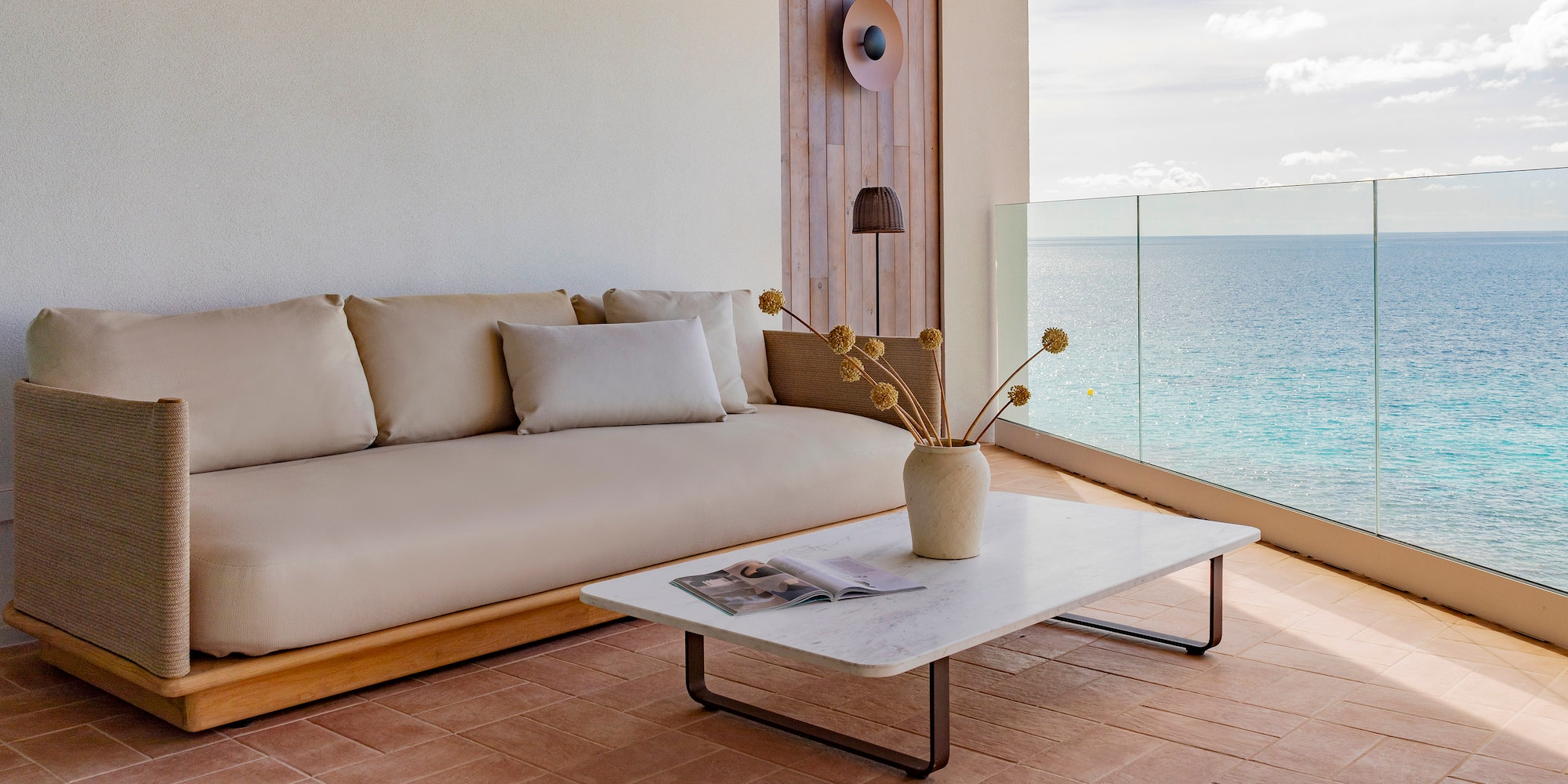 a couch and coffee table on a deck with a view of the ocean