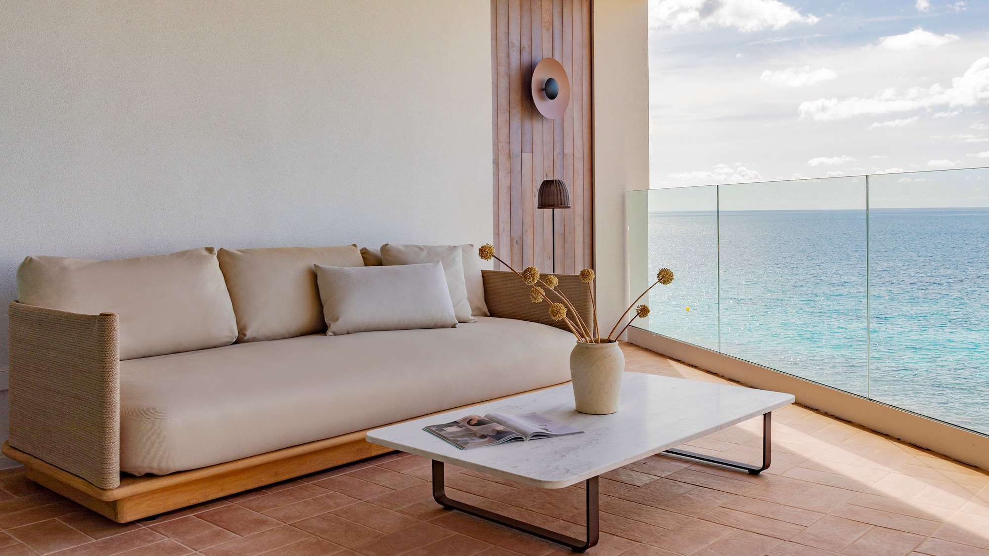 a couch and coffee table on a deck with a view of the ocean
