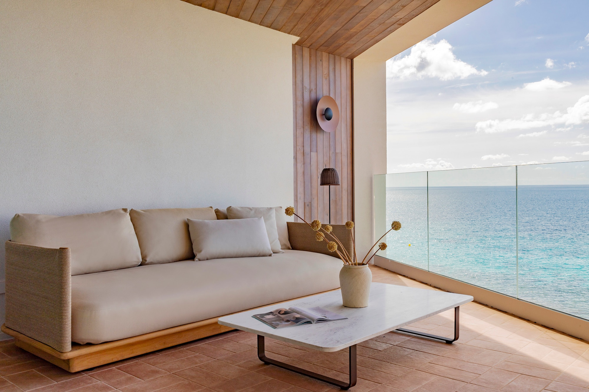 a couch and coffee table on a deck with a view of the ocean