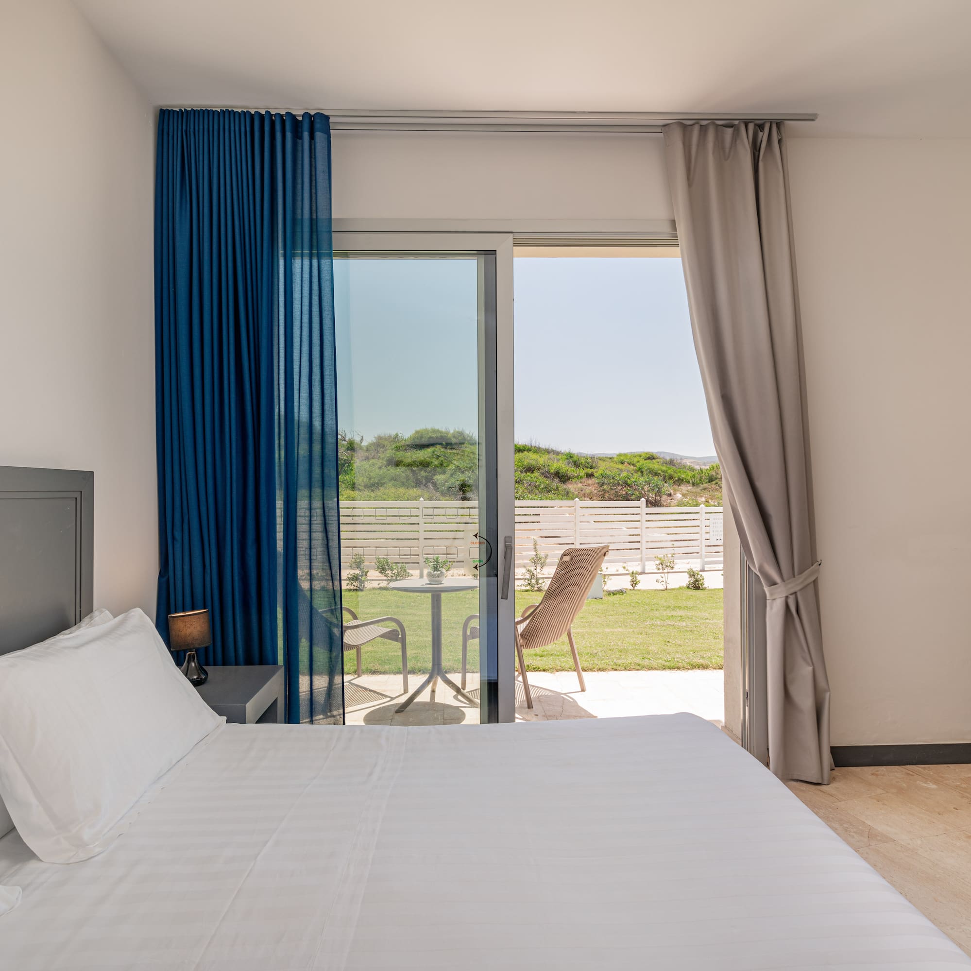 a bed with a glass door leading to a lawn