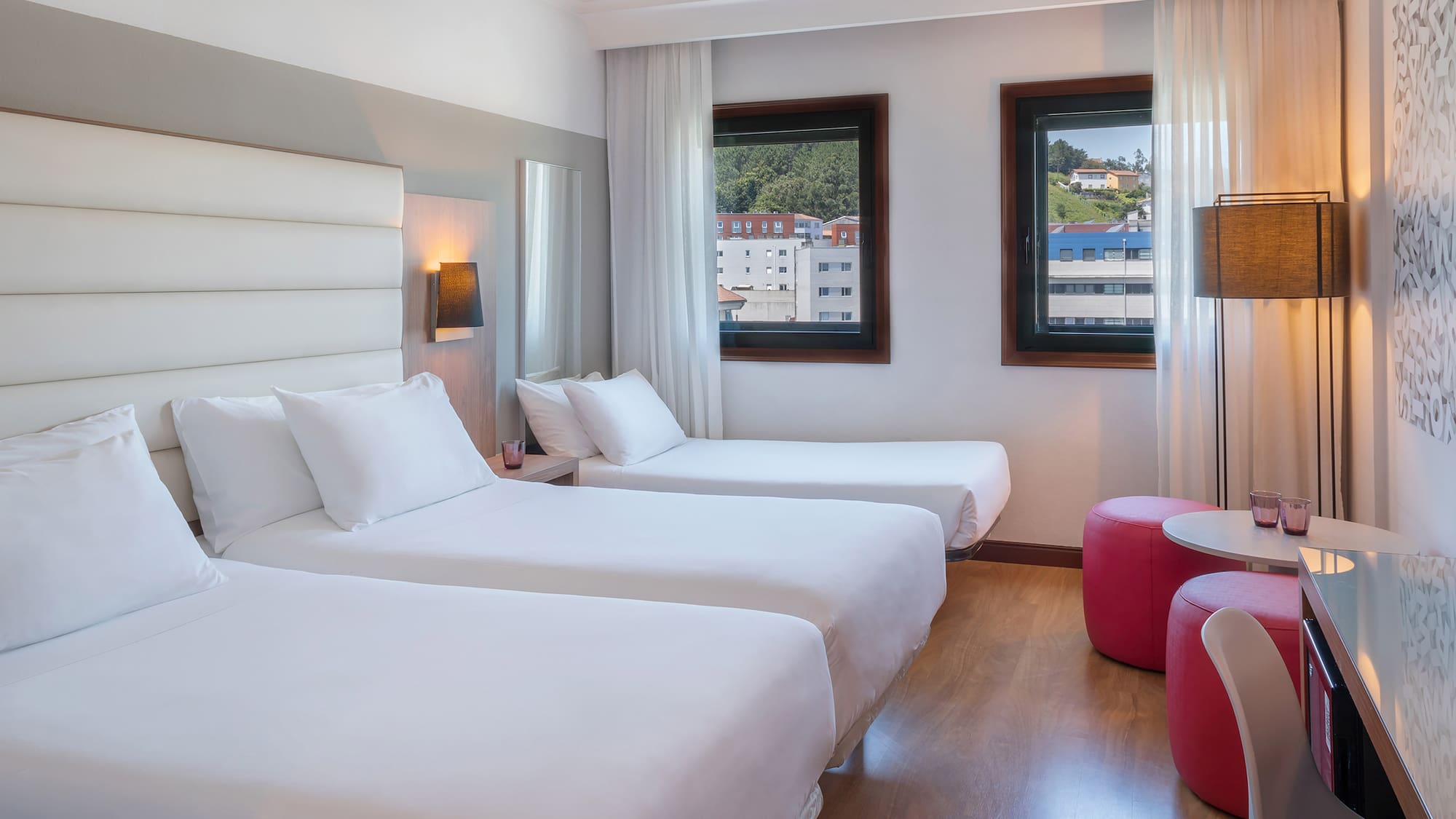 Triple hotel room with three single beds, white bedding, and city view.