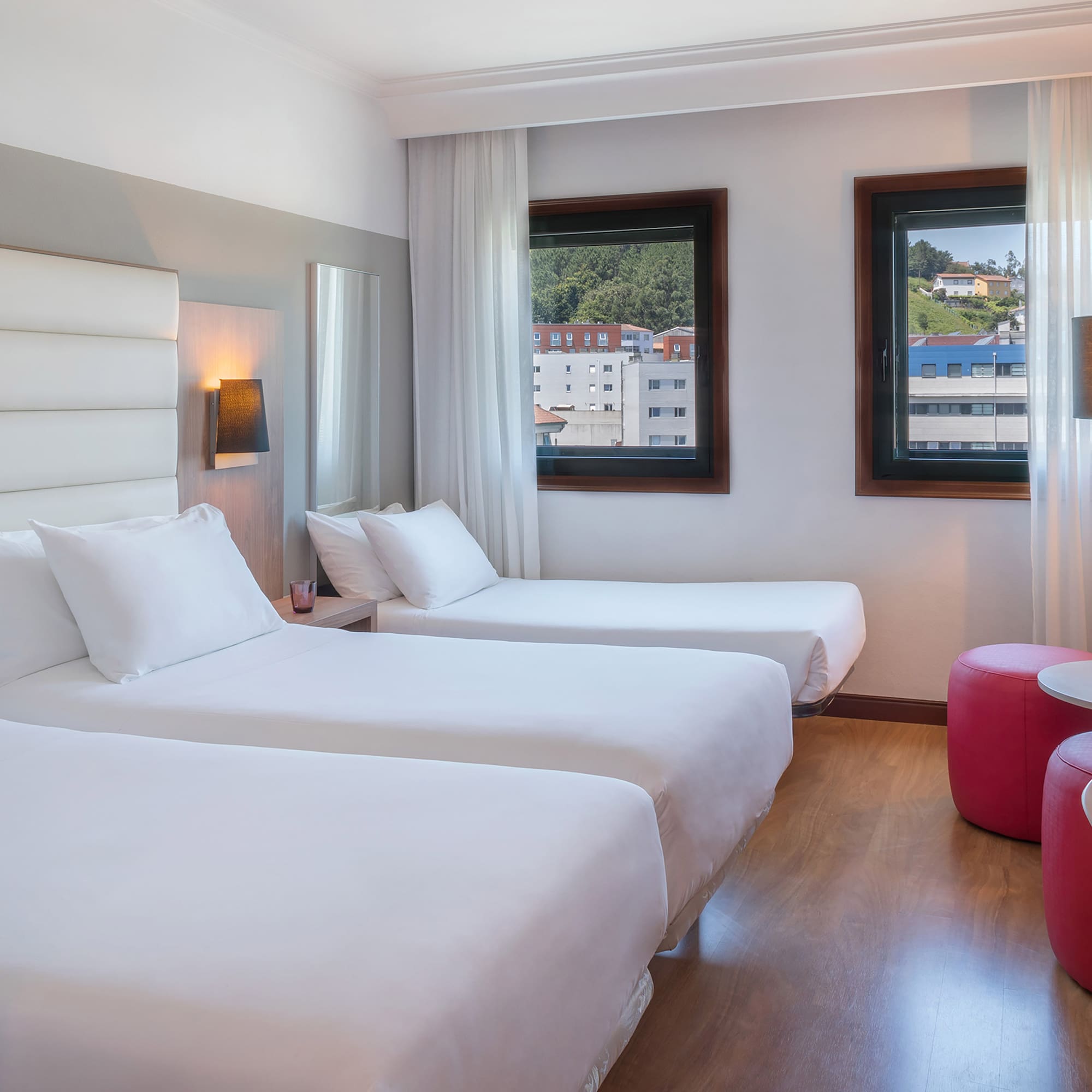 a room with two beds and a red stool