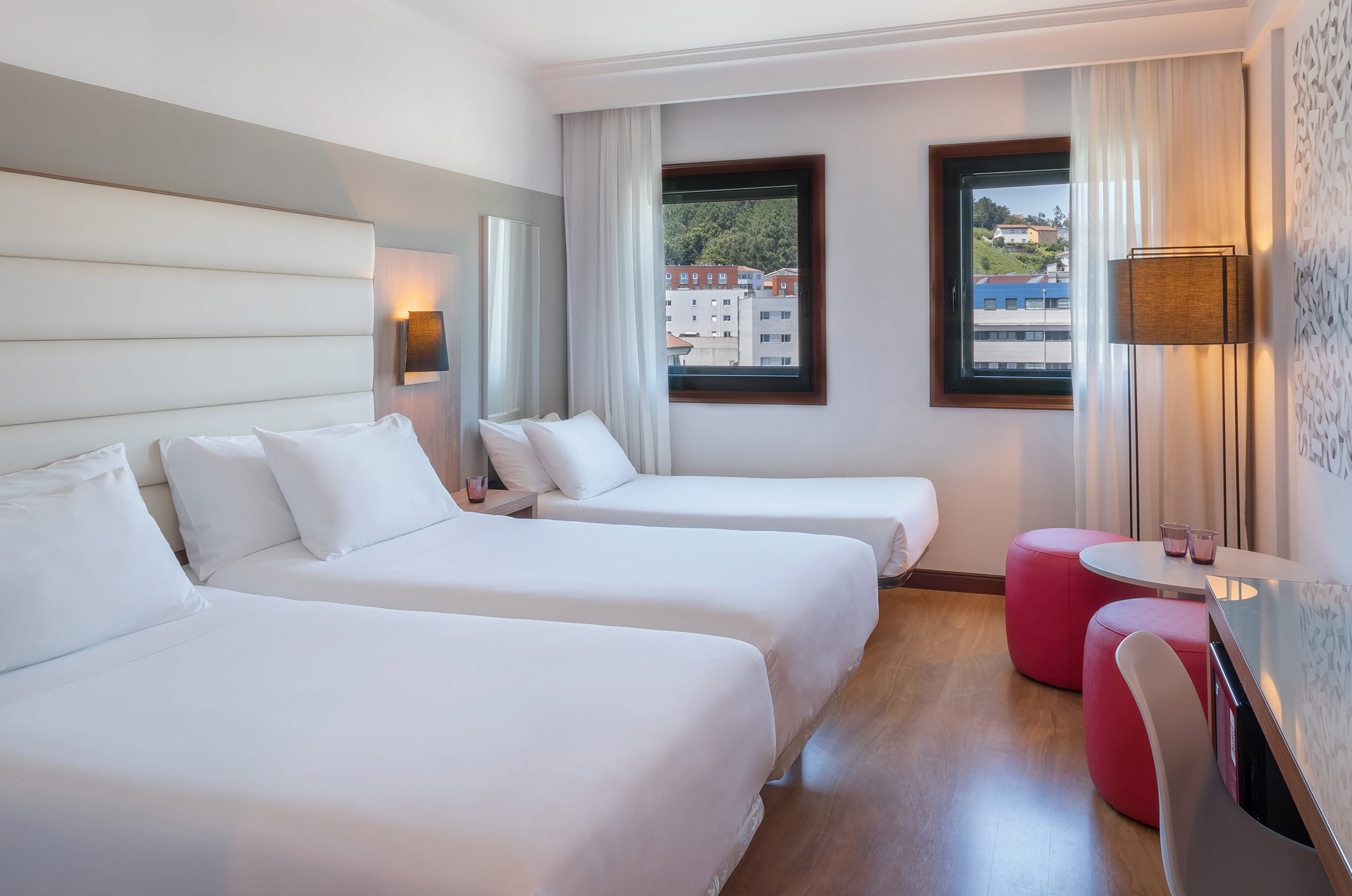 Triple hotel room with three single beds, white bedding, and city view.
