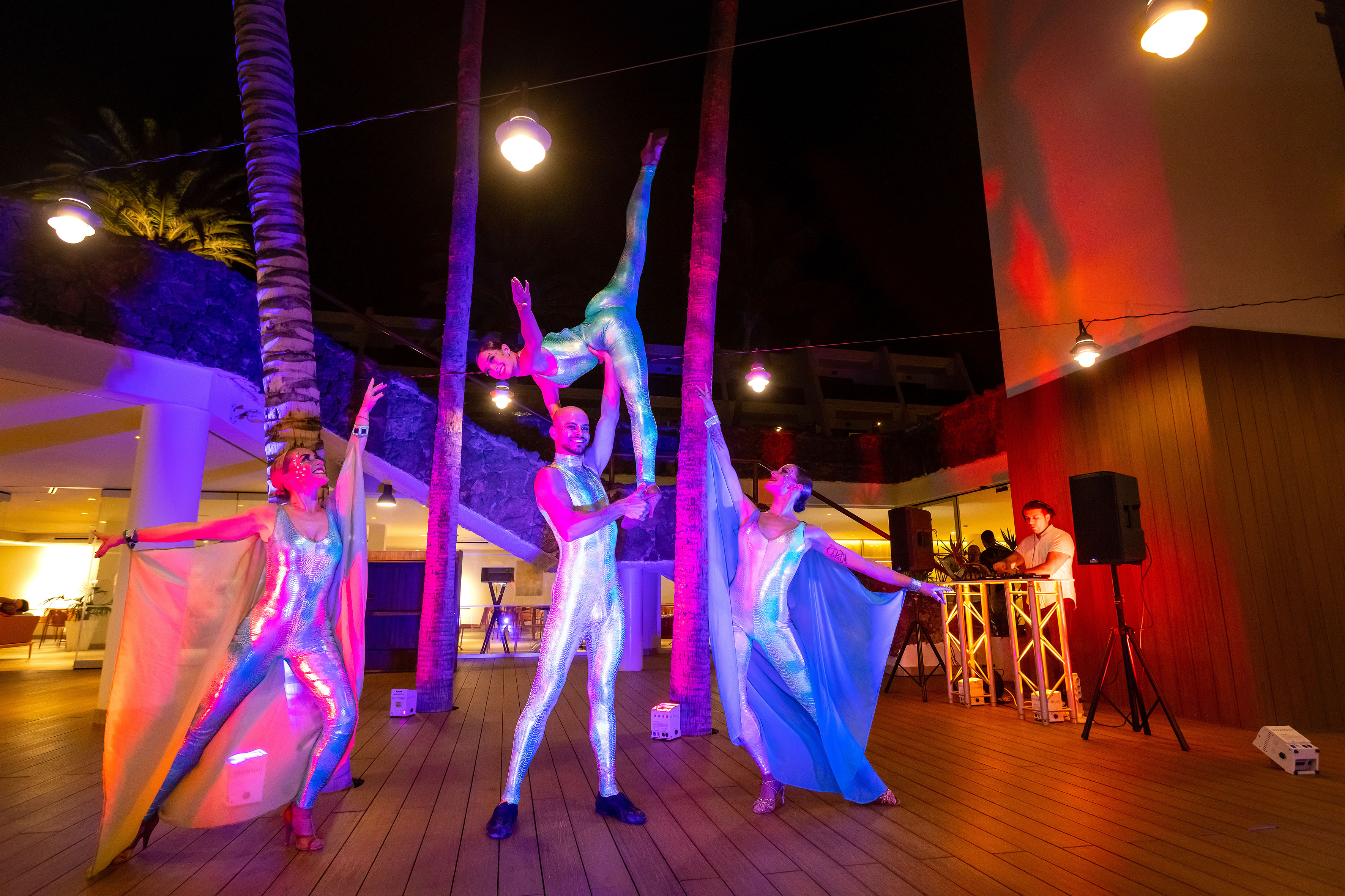 Acrobatic performers in vibrant costumes under colorful lights at a night show.